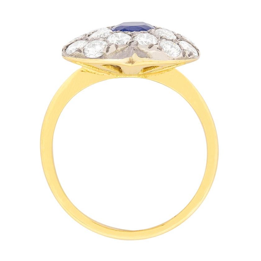 In the centre of this heart shaped ring is a cushion cut sapphire. It weighs 0.50 carat and is a natural stone. It has a rich blue colour and is rib over set. Surrounding the sapphire are grain set, round brilliant diamonds. They are G in colour and