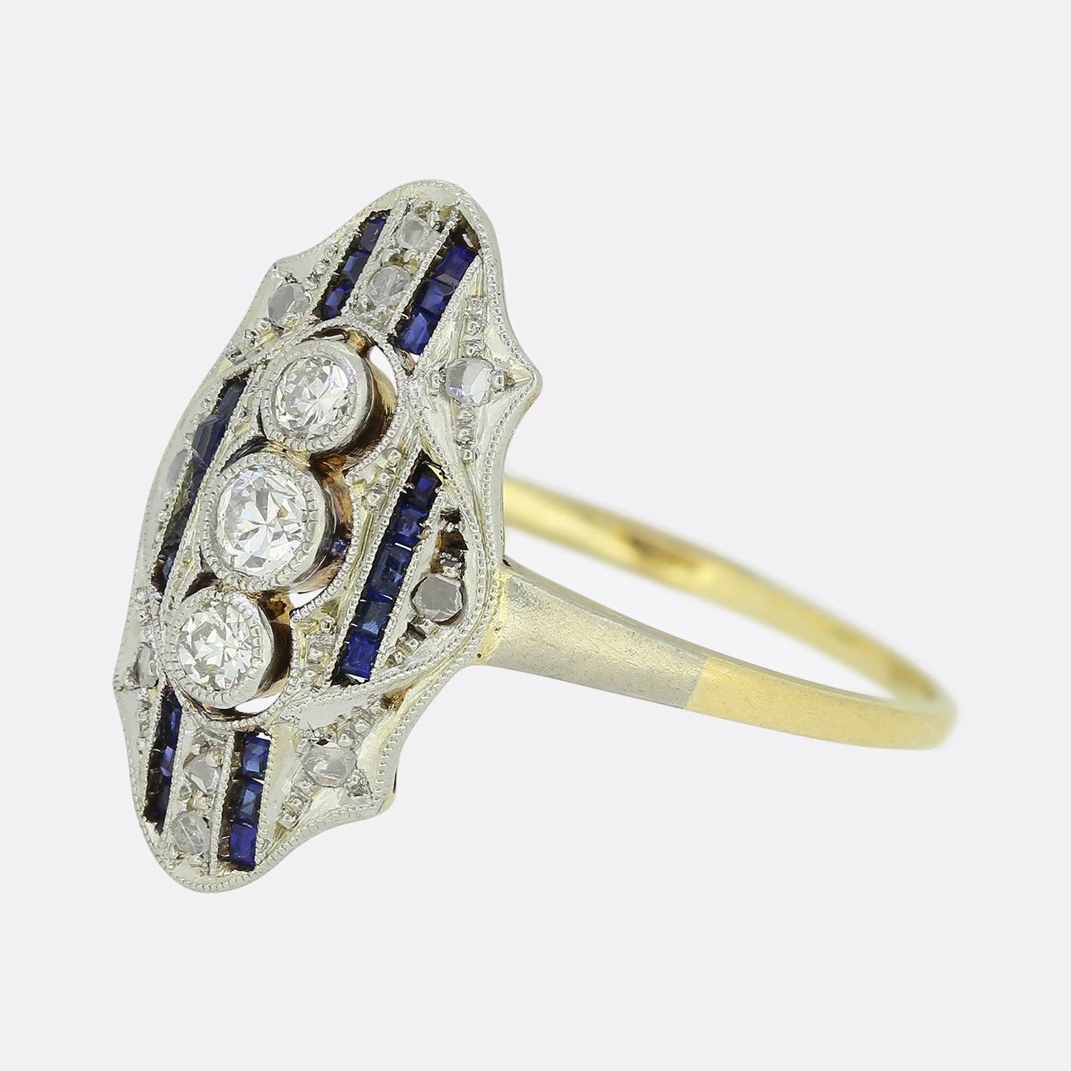 Here we have an excellently crafted sapphire and diamond ring from a time when the Art Deco style was at the forefront of design. This three-dimensional piece presents a trio of openly milgrain set round brilliant cut diamonds in a vertical line