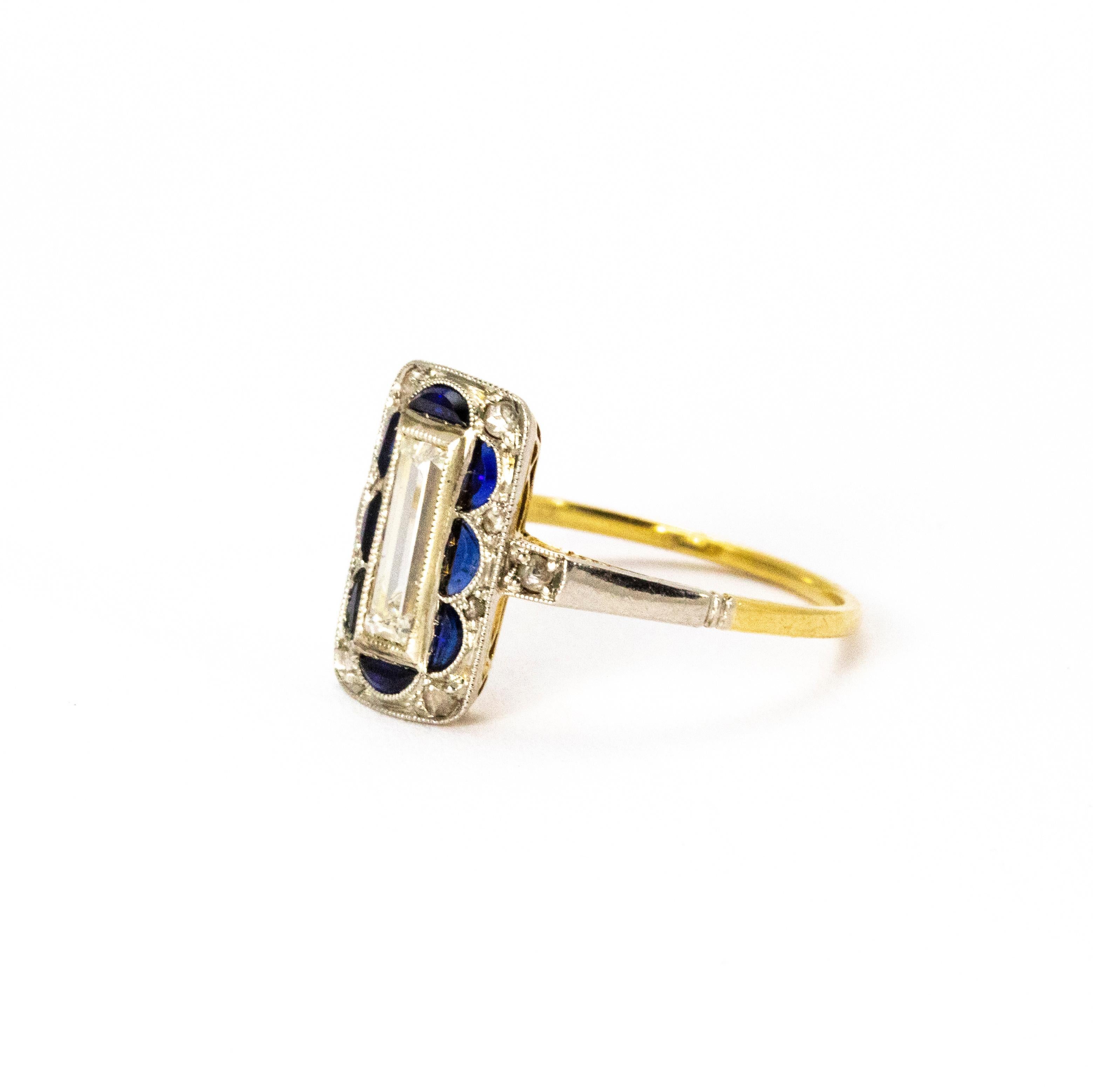 A brilliant Art Deco panel ring. Set with a beautiful white emerald cut diamond weighing 75 points surrounded by eight semicircular blue sapphires. Between the curves of the sapphires and onto the shoulders sit a further ten diamonds. Modelled on