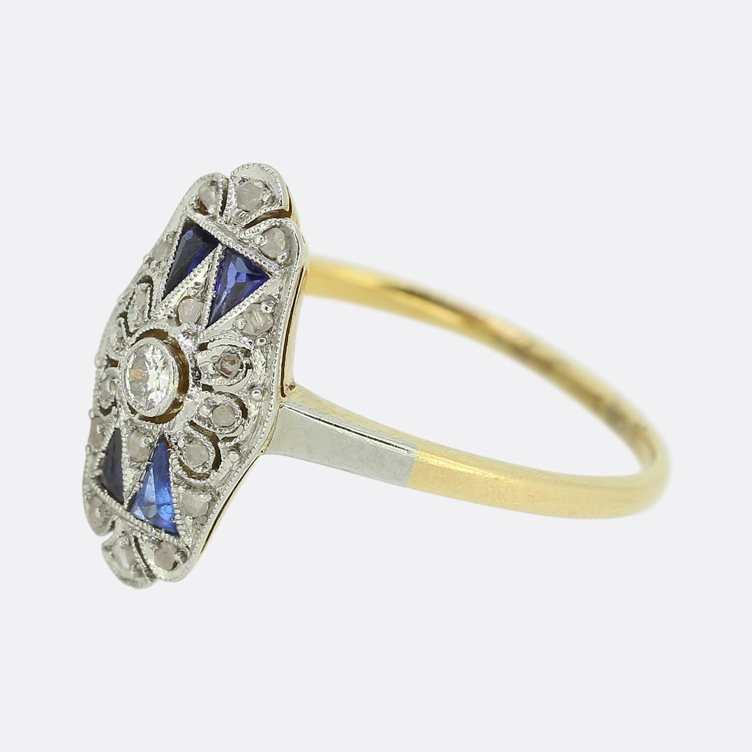 Here we have a beautifully detailed ring crafted at a time when the Art Deco style was at the height of design. 

The tone of the piece is set by four triangular cut sapphires which are set in pairs above and below a pierced mid section. A single