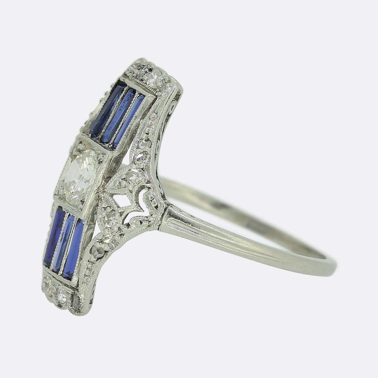 Ecco un eccezionale anello con zaffiro e diamante realizzato in un'epoca in cui lo stile Art Déco era all'avanguardia nel design. Il tono del pezzo è dato da un trio di zaffiri dritti a forma di baguette che si trovano al di sopra e al di sotto di