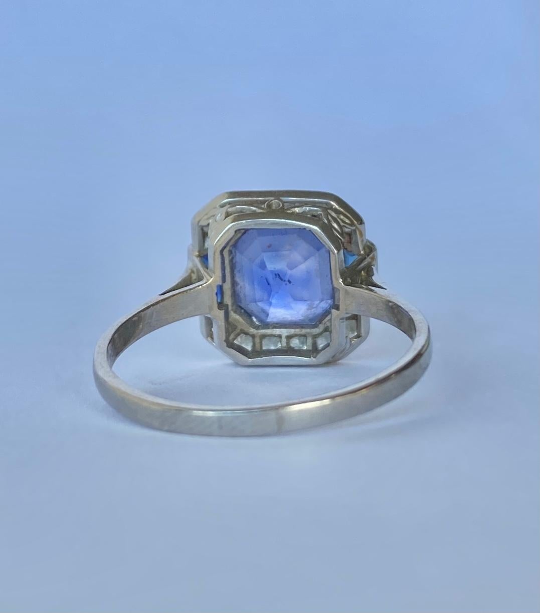 This stunning ring holds a central emerald cut sapphire measuring approx 4carat. The sapphire is natural with no heat treatment. Either side of this sapphire are two smaller step cut trapezium sapphires. Above and below the large sapphire is a row