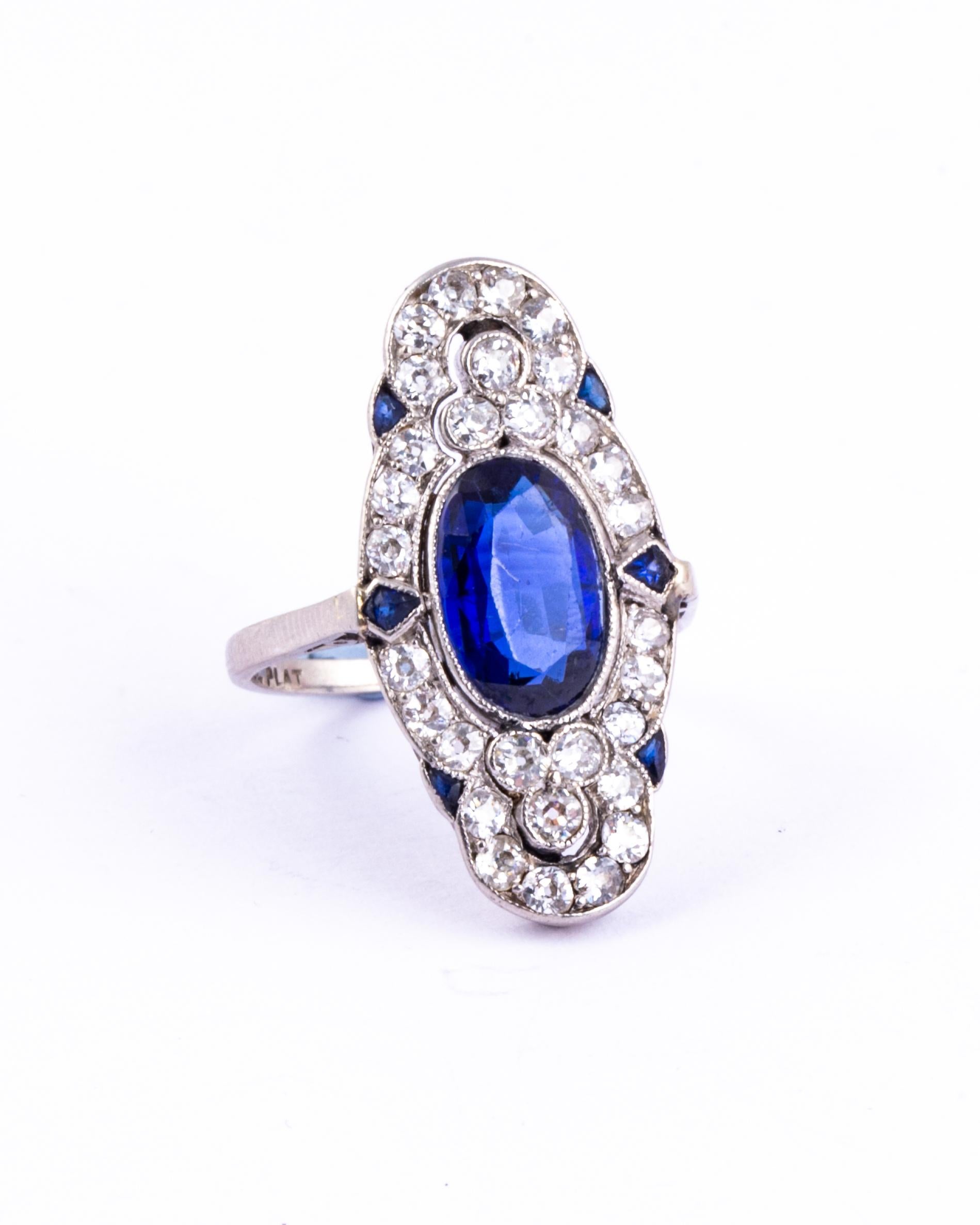 This classic Art Deco panel ring is a stunning piece. At the centre is a sapphire measuring approx 2ct and surrounding it on a decorative frame are size smaller sapphires and sparkling diamonds. The trefoil of old mine cut diamonds sit all around