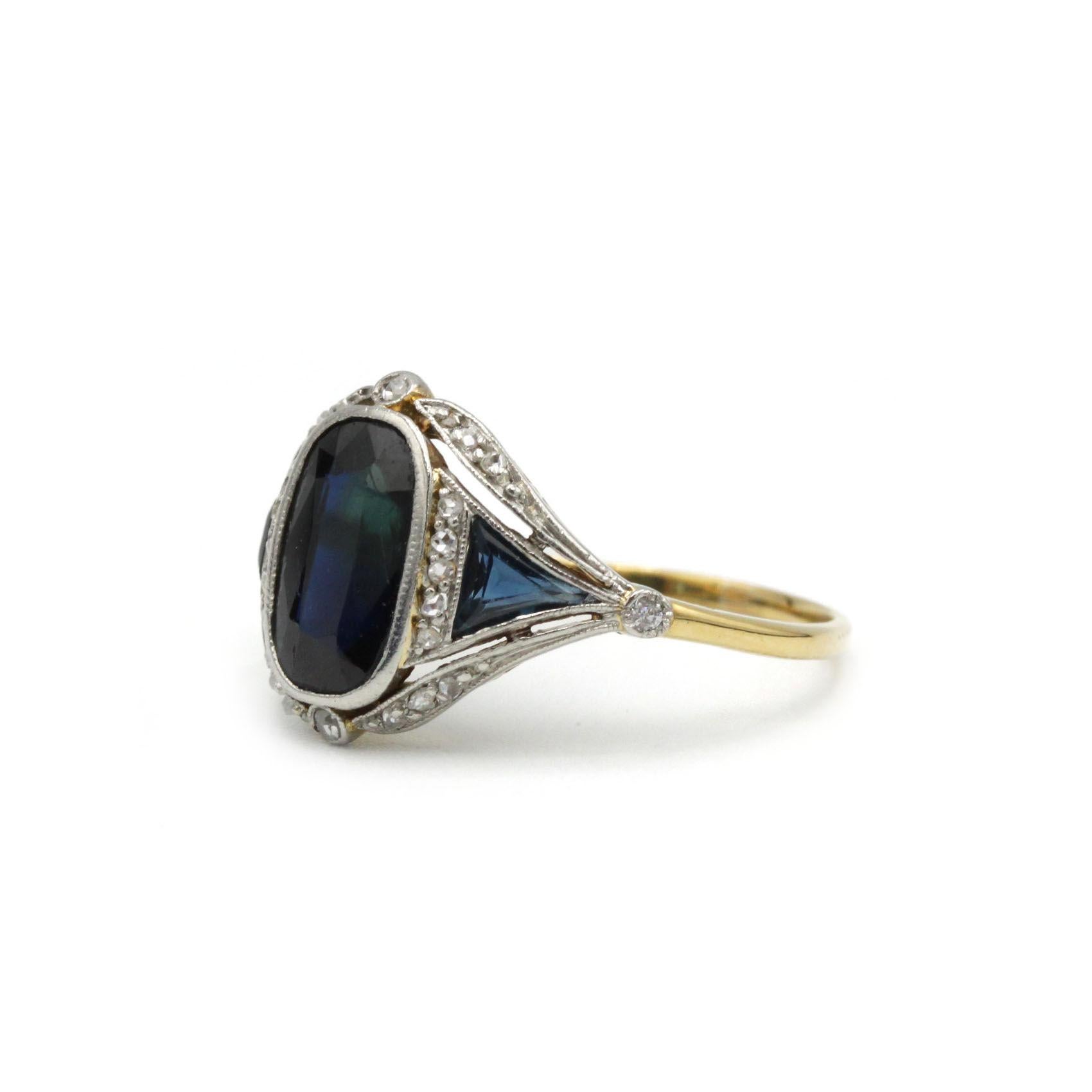 A true testament to Art Deco elegance, this vintage sapphire and diamond ring radiates sophistication and balance. At the heart of the design lies a deep blue sapphire of approximately 2 carats, whose rich color is enhanced by an architectural
