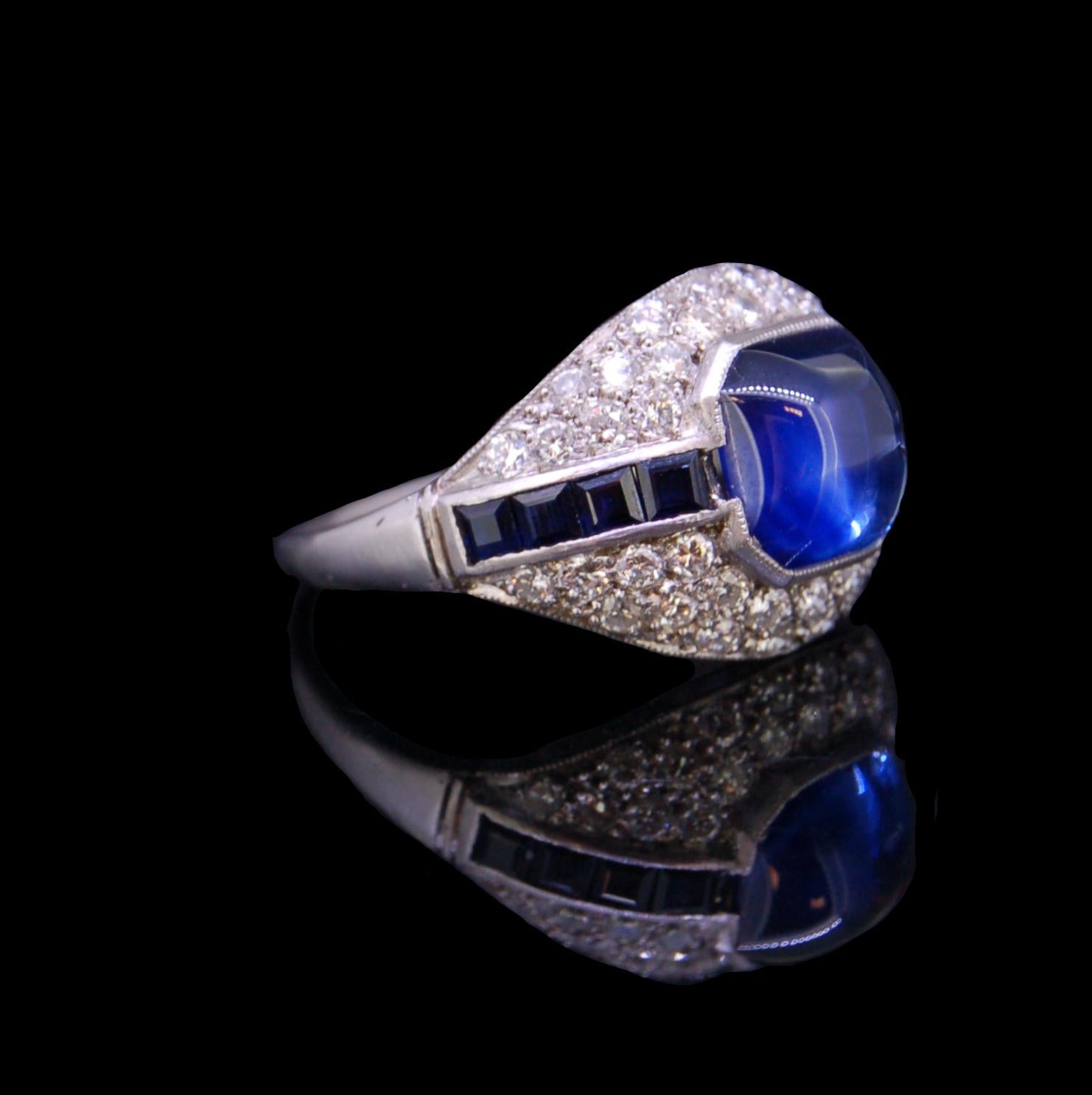 ART-DECO STYLE SAPPHIRE AND DIAMOND RING, centrally set with a cabochon cut sapphire, flanked by square cut blue sapphires and brilliant cut diamonds. Sapphires totalling approx. 3.80 ct. Diamonds totalling approx. 0.84 ct. Size Q. 5.1 grams.