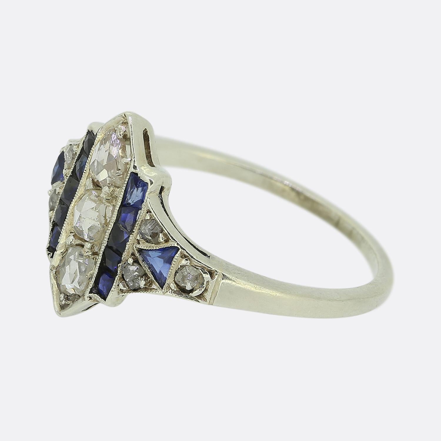 Here we have a fabulous sapphire and diamond cluster ring showcasing a typical geometric design of which we so closely associate with the Art Deco style. A trio of sizeable rose cut diamonds sit atop of one another at the centre of the face which