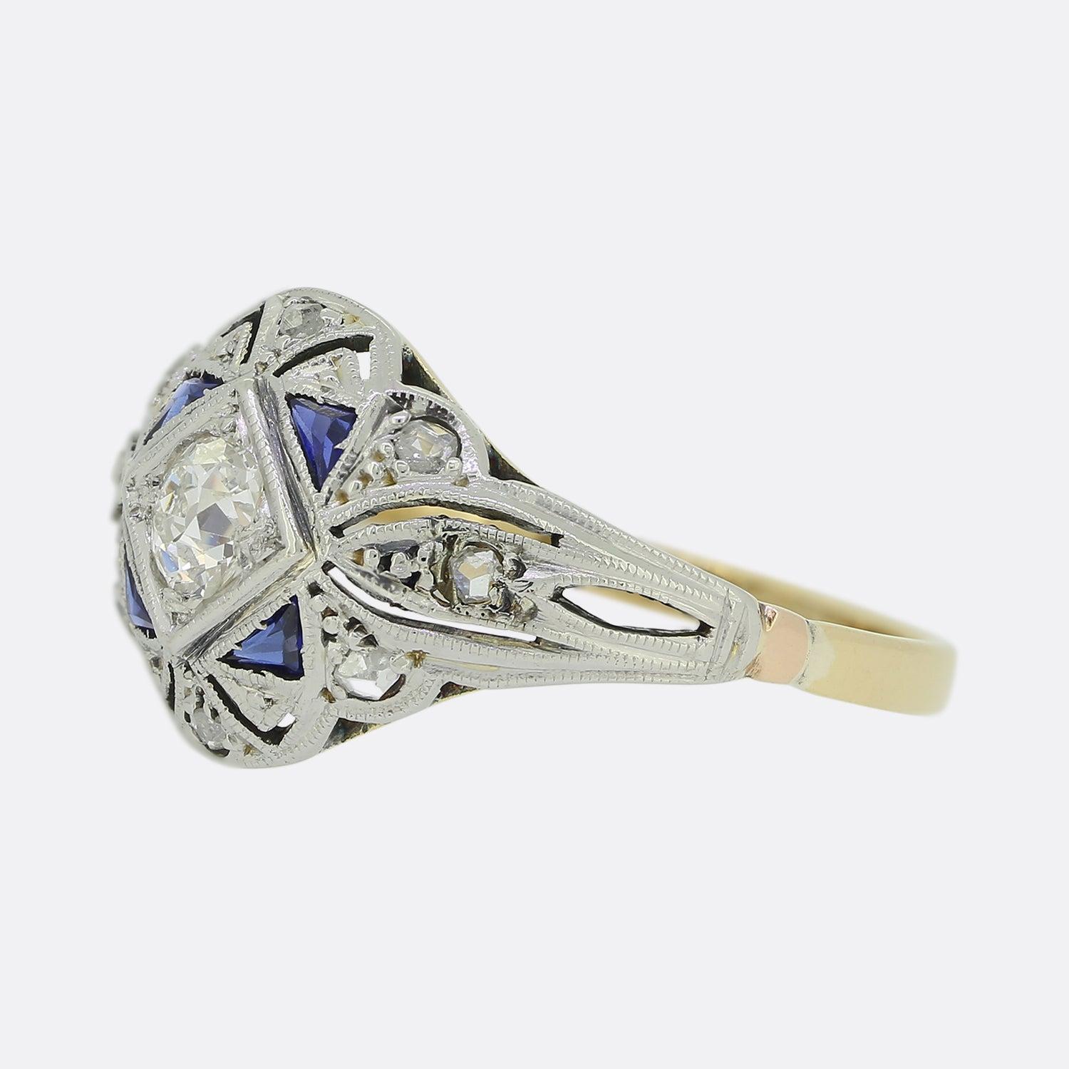 This is a delightful Art Deco sapphire and diamond ring. Crafted from 18ct gold, this piece showcases the archetypal decadence of the style including handcrafted pierced open work, the fine milgrain bordering and the sleek geometric settings.