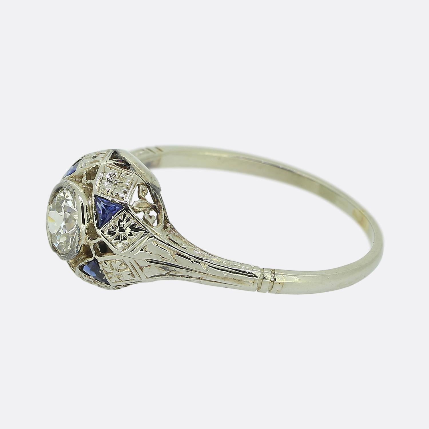 Here we have a splendid Art Deco sapphire and diamond ring. Crafted in platinum, this piece showcases absolutely sublime attention to detail including the handcrafted pierced work, the engraved foliated designs and the open fleur-de-lis themed under