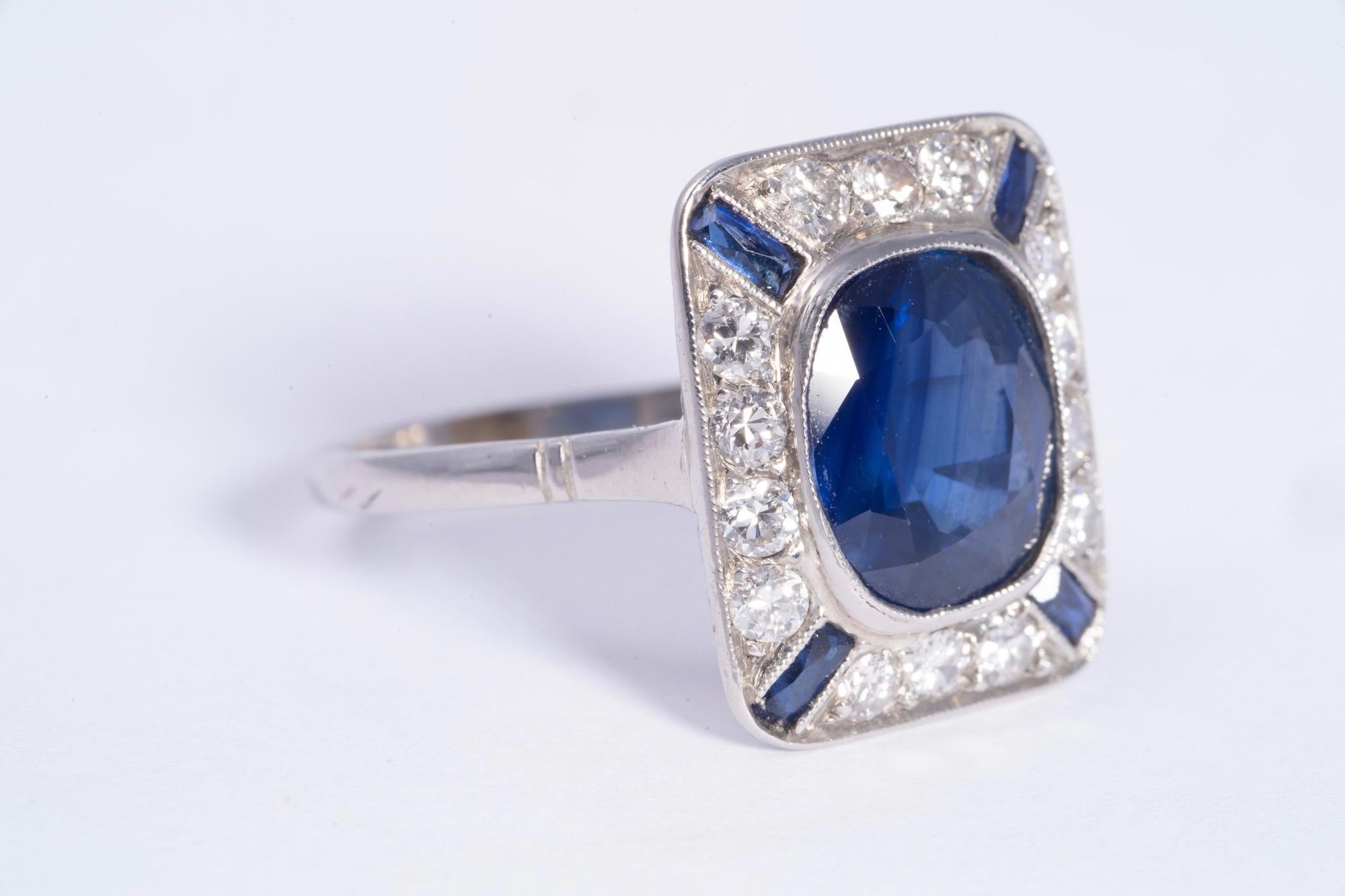 Cushion cut blue sapphire weighing approximately 3.20cts. There are 14 round brilliant cut diamonds around the center blue sapphire that weigh approximately .70cts total. There are 4 blue sapphire baguettes that weigh approximately .40cts total. The