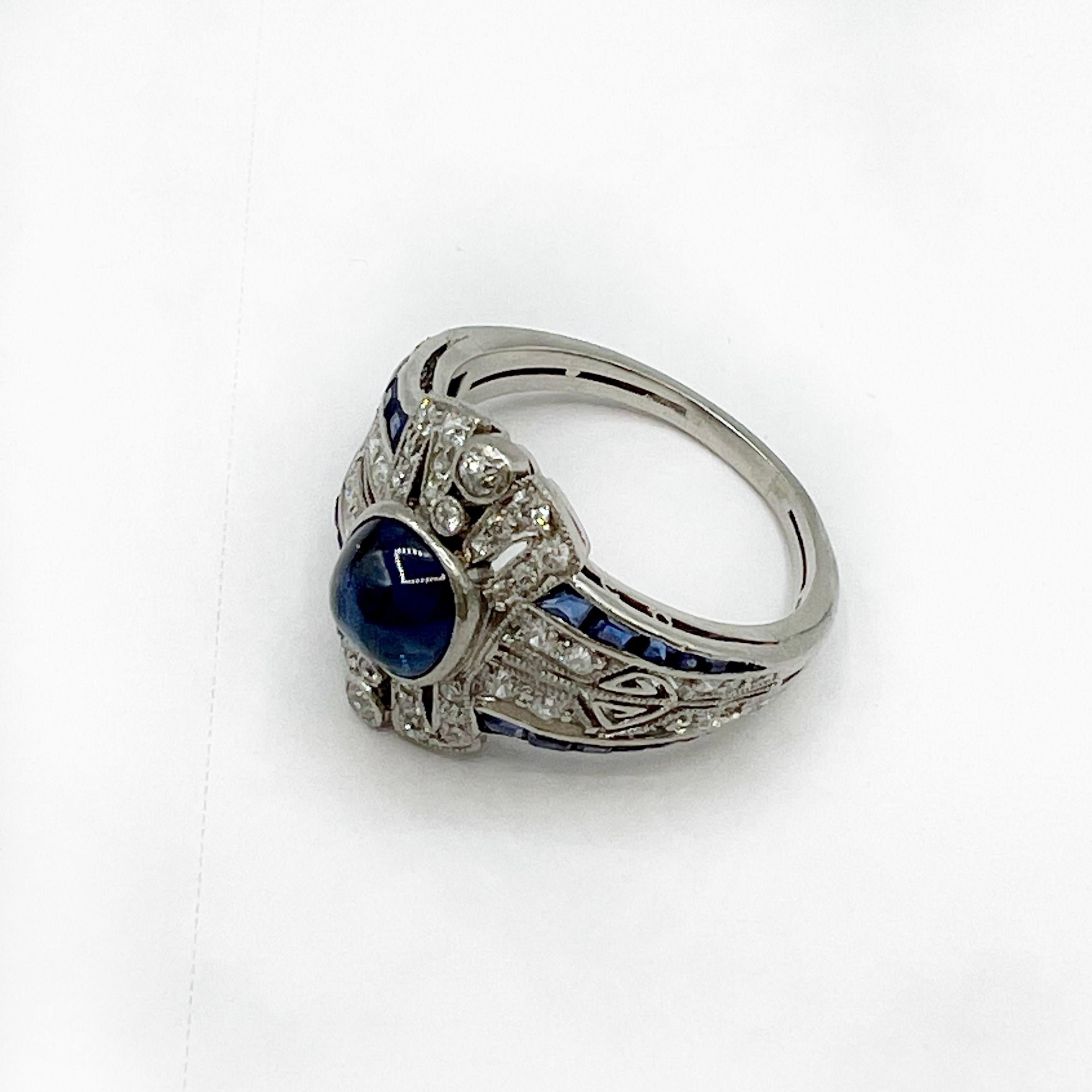 This stunner is a beautiful Art Deco sapphire and diamond ring. The center sapphire is a cabochon that is faceted on the bottom and reflects the light beautifully. The size of the sapphire is approximately 1.0 carats.  It is made out of platinum and
