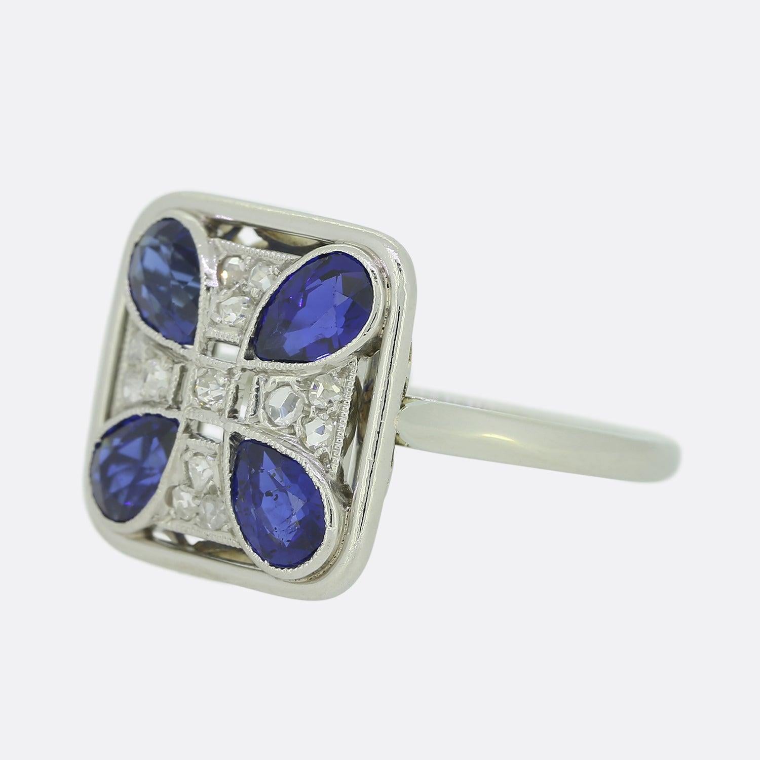 Here we have a wonderful Art Deco sapphire and diamond ring. The head of this unique piece has been crafted into the shape of  a square and showcases multiple layers upon an open structure. Four beautifully deep toned pear shaped sapphires dominate
