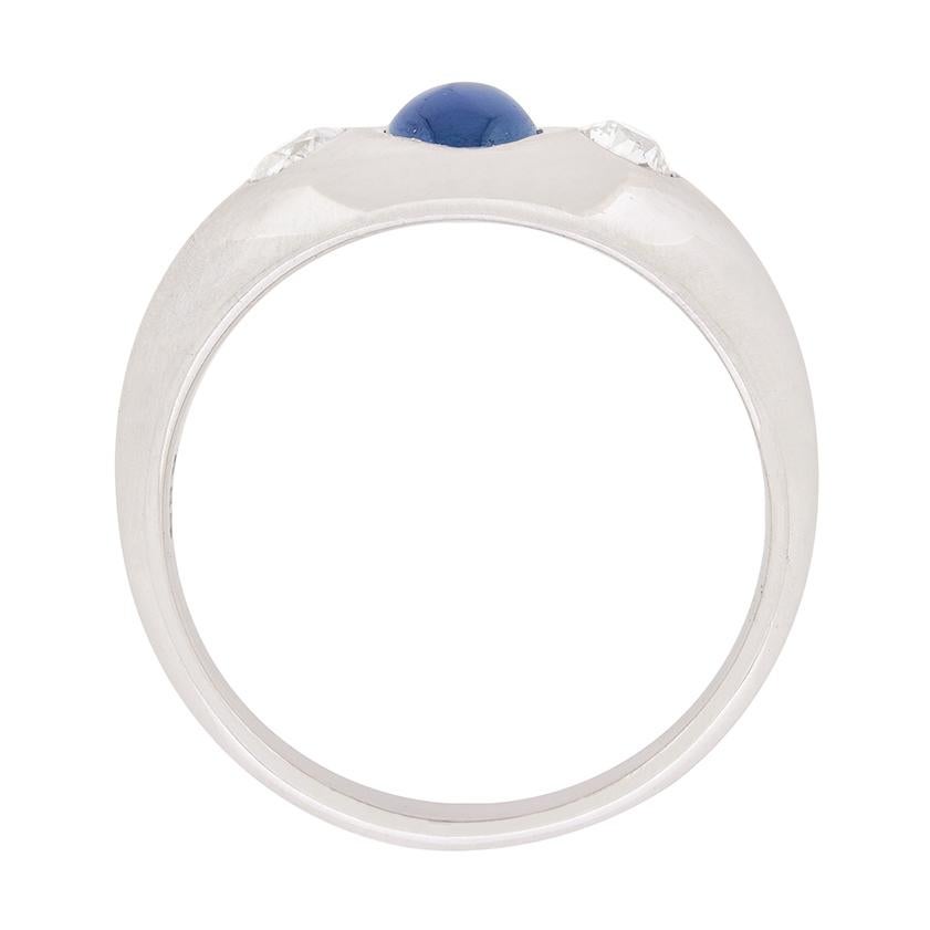 This interesting ring is more than likely American, having been made in 14 carat white gold. The sapphire in the centre weighs 0.50 carat and is an oval cabochon cut gemstone. It is a wonderful blue colour which stands out in the rub over setting.
