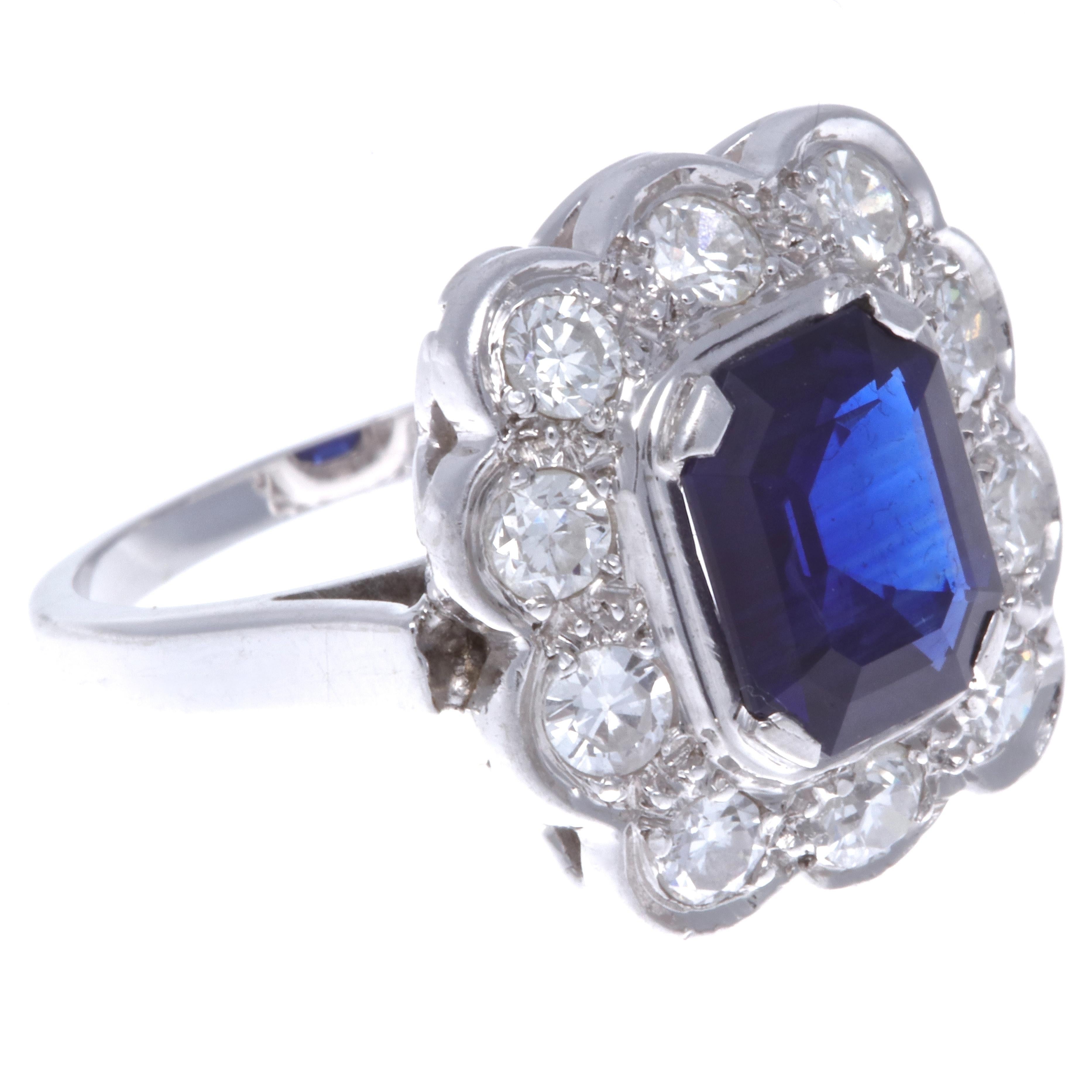 What a beautiful, yet powerful Art Deco Style Diamond 18k white Gold Cluster/Flower Motif Ring. A perfect accessory to brighten your day. This rectangular emerald cut sapphire is approximately 2.50 carats, and it adds a unique look to the cluster