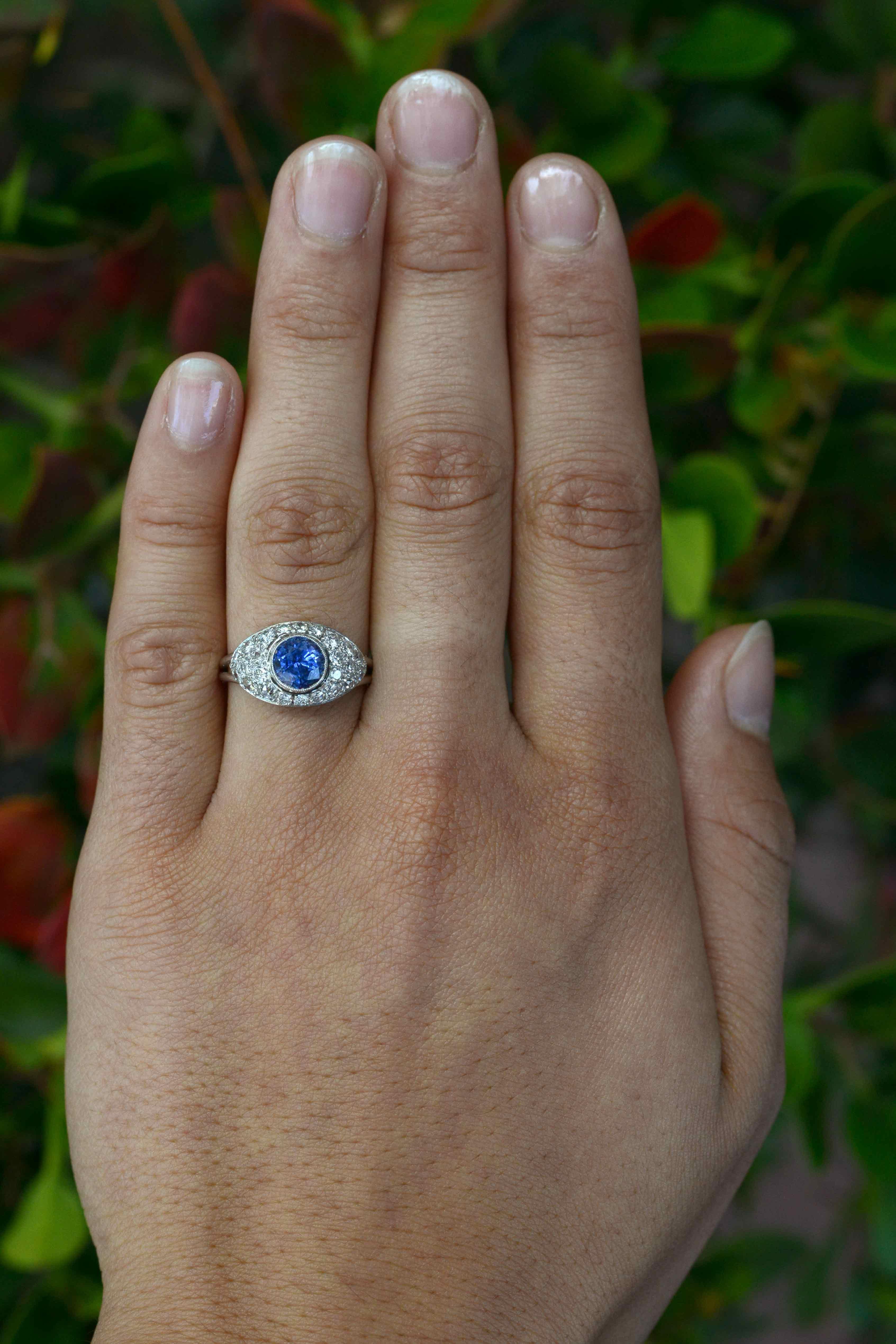 An original Art Deco style sapphire engagement ring crossing over from the Edwardian era, the platinum bombe' dome setting is encrusted with 3/4 carats of sparkling old European diamonds. Topped with the most vibrant, shimmering shade of blue with