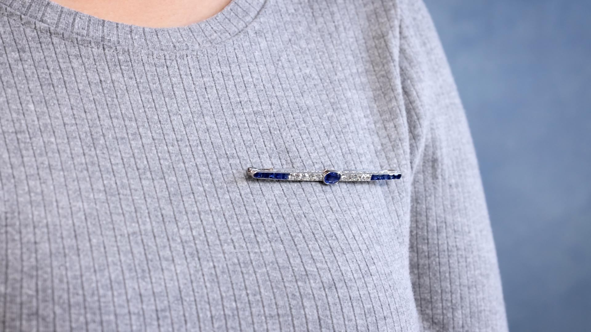 One Art Deco Sapphire Diamond Platinum Bar Brooch. Featuring one oval mixed cut sapphire weighing approximately 1.10 carats. Accented by 12 calibre cut sapphires with a total weight of approximately 1.80 carats and 10 old mine cut diamonds with a