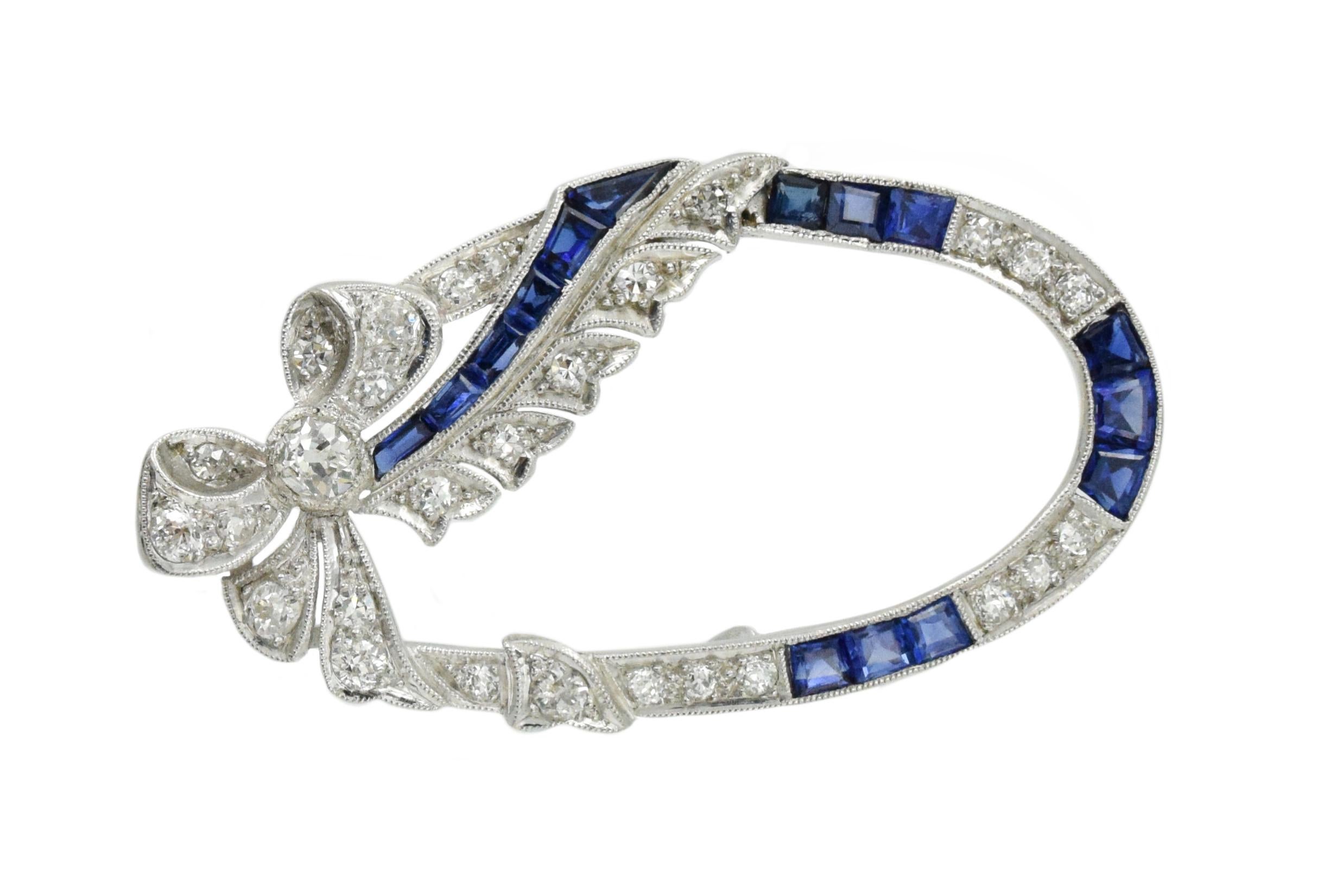 Art Deco brooch with millegrain accents. The brooch has 27 round-cut diamonds with an approximate total weight of 1.25 carats, and 15 calibre-cut sapphires with an approximate total weight of 1.50 carats. The brooch is oval shape with a diamond set