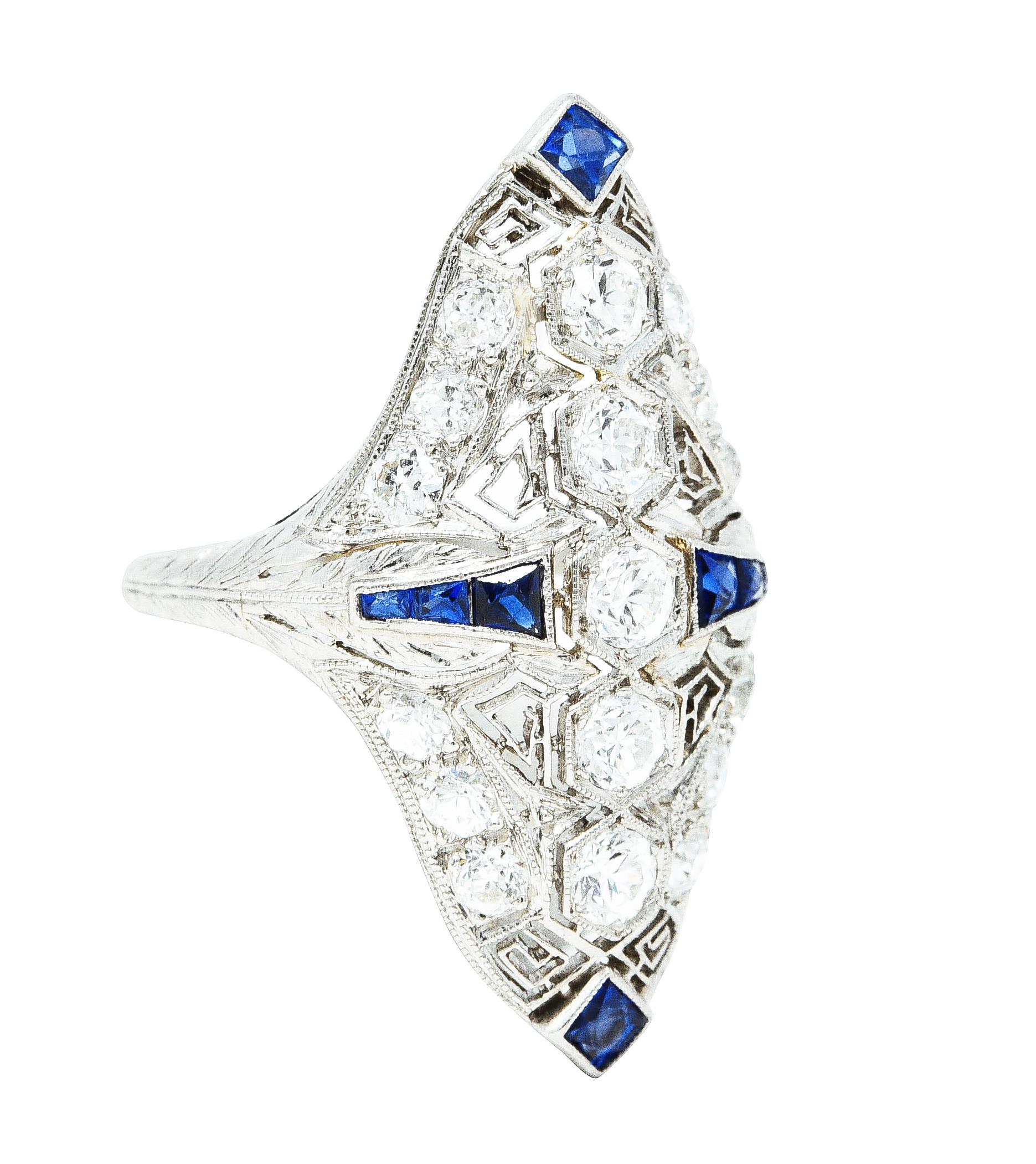 Dinner ring is designed as a navette form with pierced Greek key details. Centering a row of hexagonal forms set with old European cut diamonds. With calibré cut synthetic sapphire at each cardinal point - bright royal blue. Additional old European