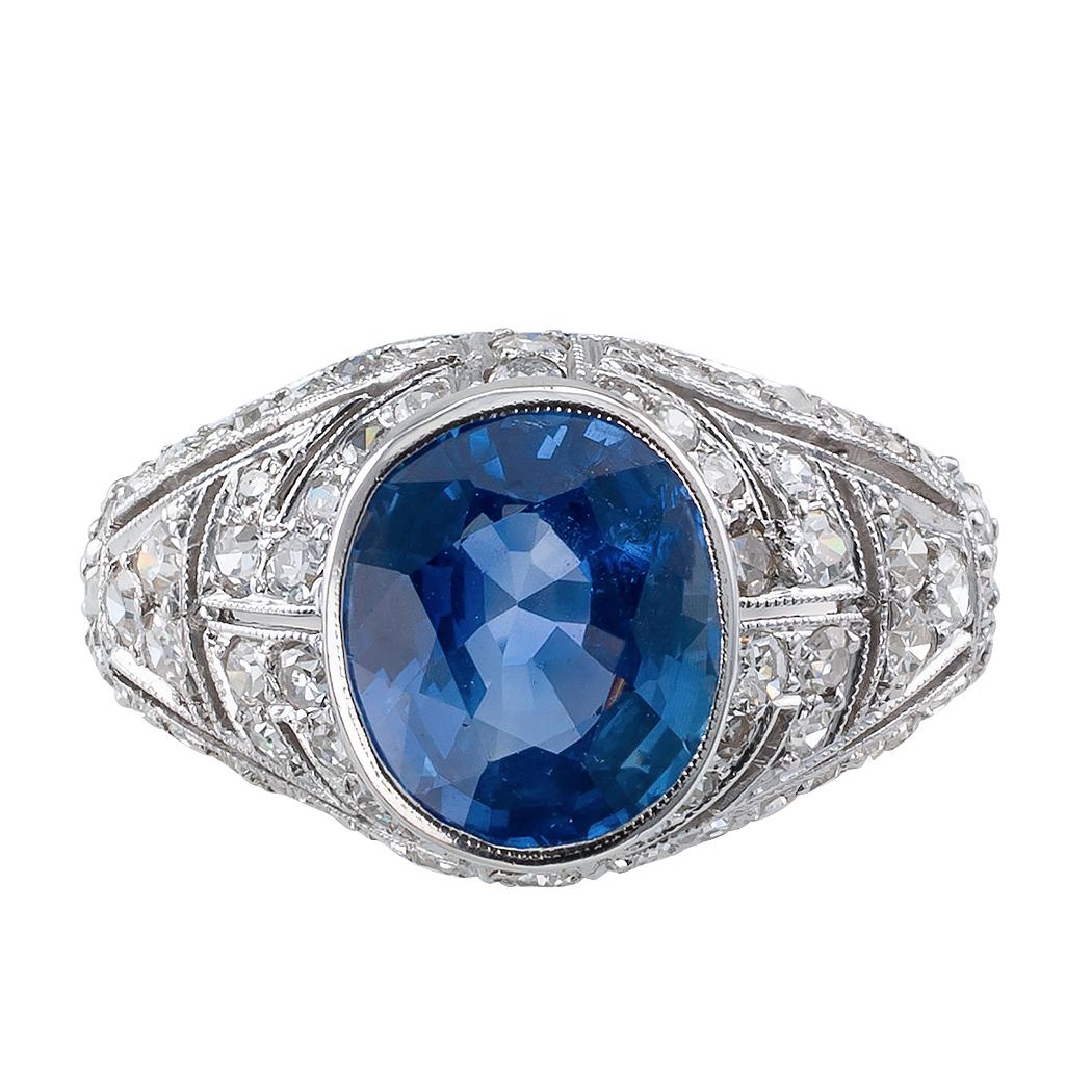 Art Deco sapphire and diamond platinum ring circa 1925. The design showcases a bezel-set, oval, blue sapphire weighing 2.47 carats, on a slightly domed platinum mounting decorated by open work, geometric motifs and milgrain, entirely frosted with