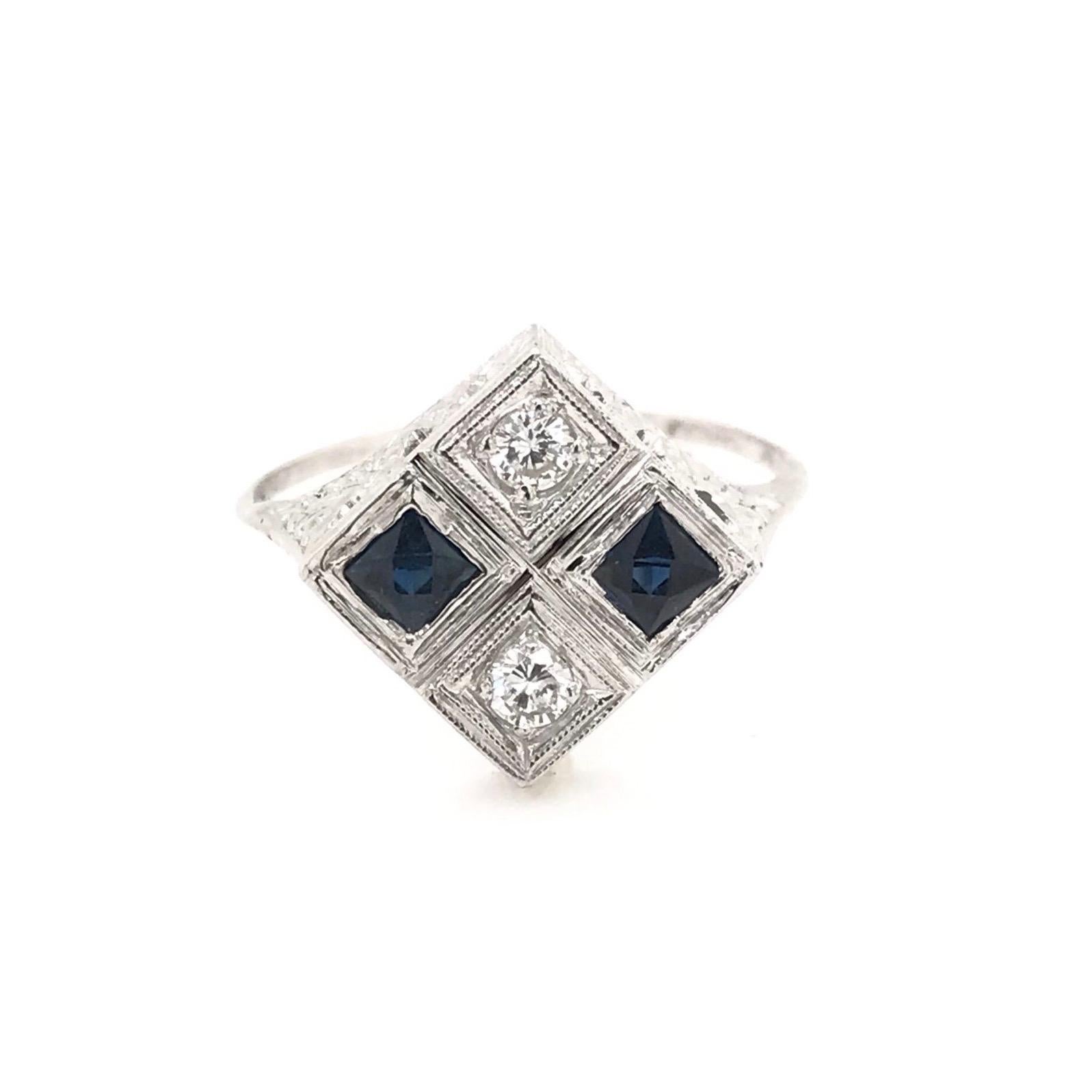 This antique piece was handcrafted during the Art Deco design period ( 1920-1940 ). The 18k white gold setting features two sparkling diamond accents arranged north to south as well as two custom cut deep blue sapphire accents arranged east to west.