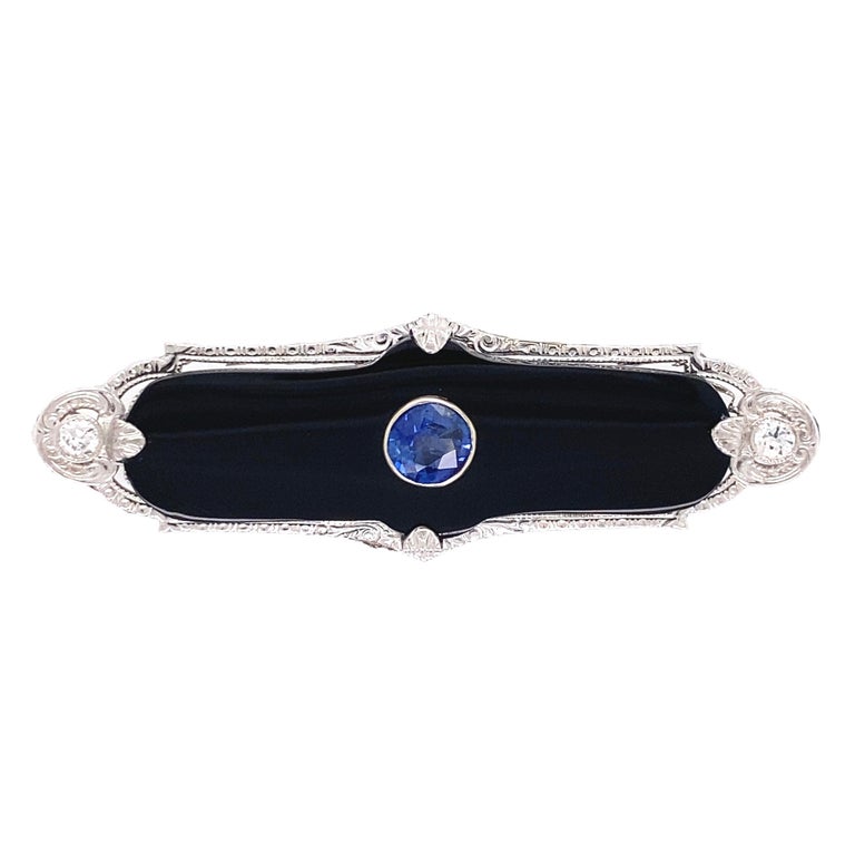 Beautiful Art Deco Sapphire in Onyx and Diamond Gold Bar Pin centering a 0.80 Carat Round Sapphire accented by Diamonds, approx. 0.14tcw and at the ends. Measuring approx. 2