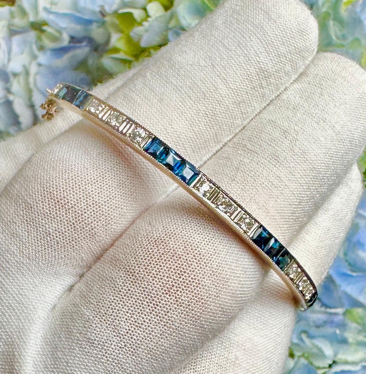 This is a gorgeous antique Art Deco Bangle Bracelet with 12 Square Cut Channel Set Sapphires and 11 Old Mine Cut Diamonds in 14 Karat White and Yellow Gold.  The elegant and classic design is exquisite.  The bracelet alternates groups of three