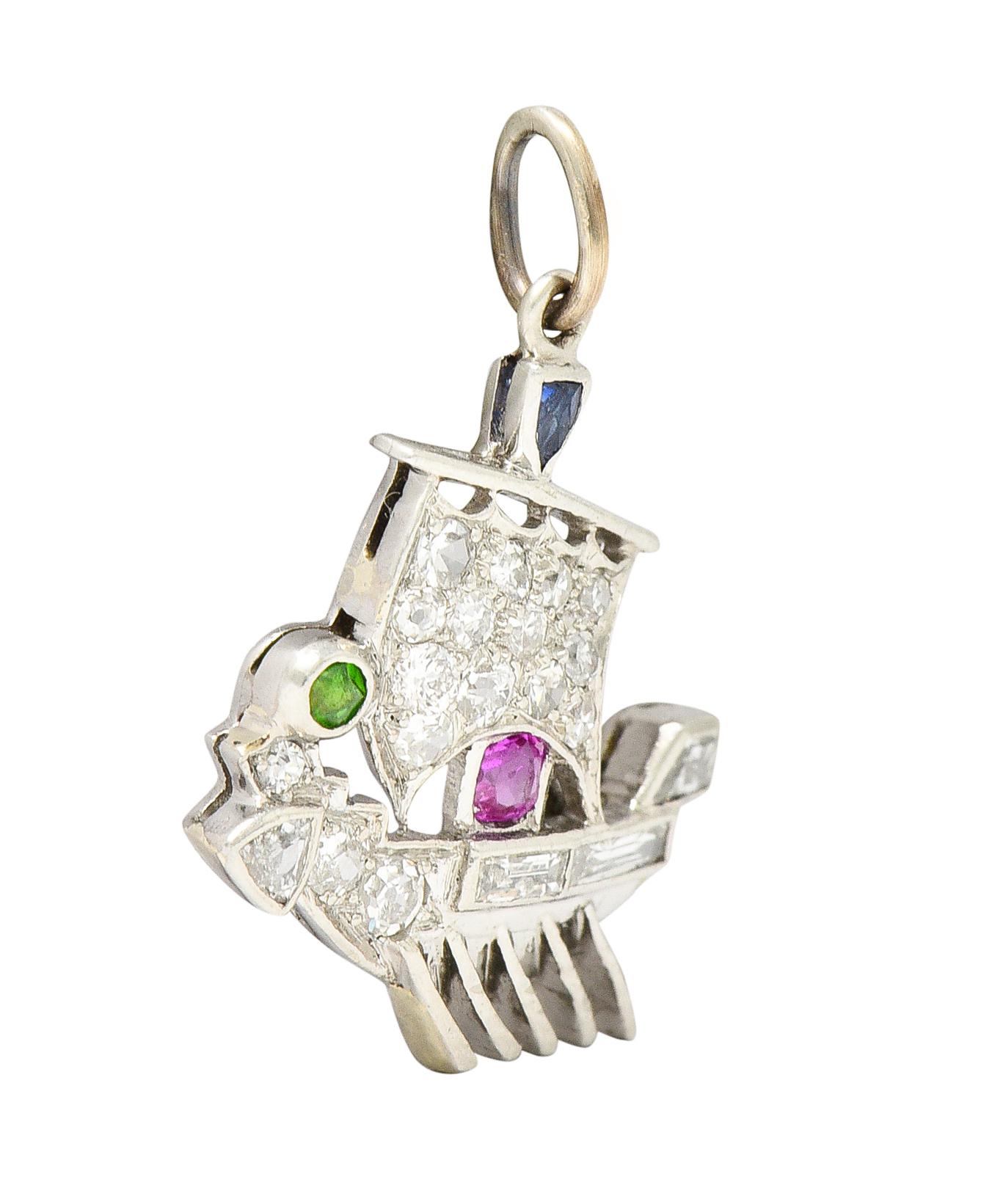 Charm is designed as a geometrically styled Viking longboat with a cast sail and angled rowing paddles. Featuring calibrè cut accents of a red ruby, blue sapphire, and bright green demantoid garnet. Set throughout by baguette and old single cut