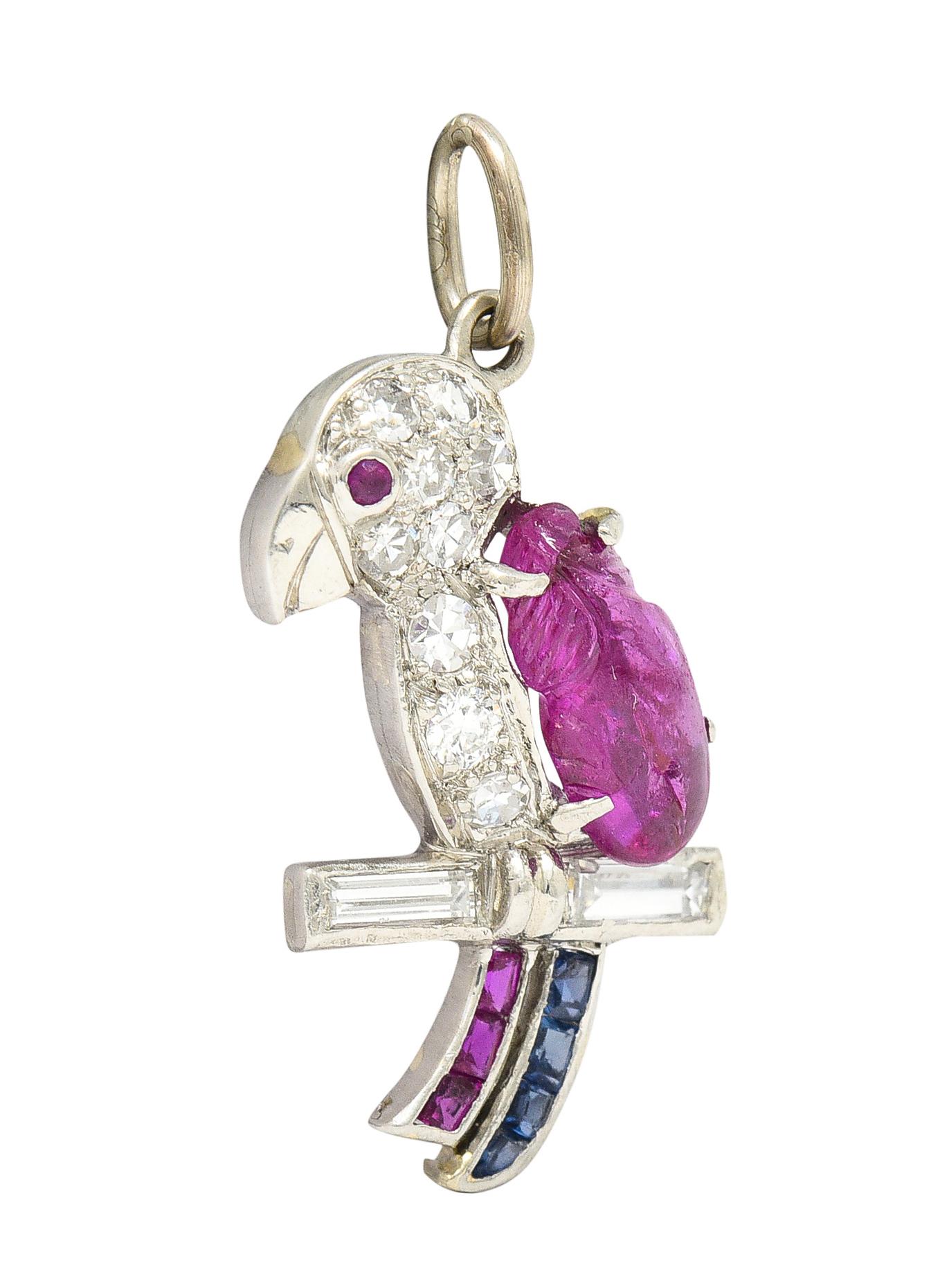 Designed as a perched parrot on a baguette cut diamond branch. Featuring a Mughal carved ruby cabochon weighing approximately 1.12 carats. With ruby eye and channel set calibré cut rubies and sapphires as tail plumage. Weighing collectively