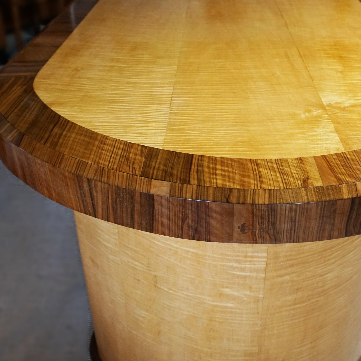 An Art Deco table with satin birch veneers and figured walnut banding. tabletop sits over two crescent shaped pedestals linked by a Satin Birch and walnut veneered stretcher. Veneered all round. This table can be used as a dining table, centre table