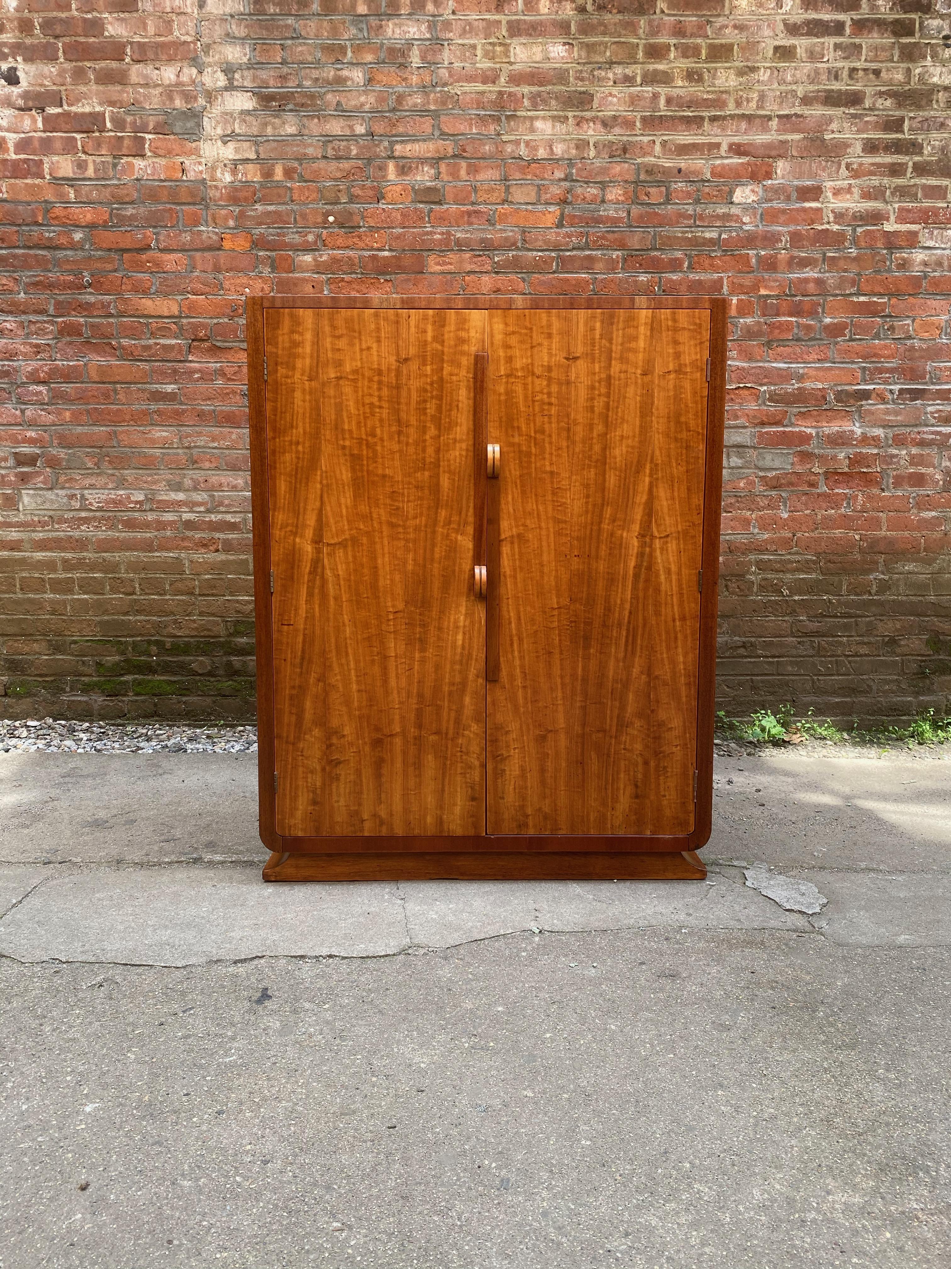 Stunning figured Satinwood and mahogany Art Deco dresser that retailed at Fennell's, Mount Vernon, Westchester, New York, circa 1930-1940. Satinwood veneers decorate the doors and top while darker Mahogany decorate the sides and banded edge. The