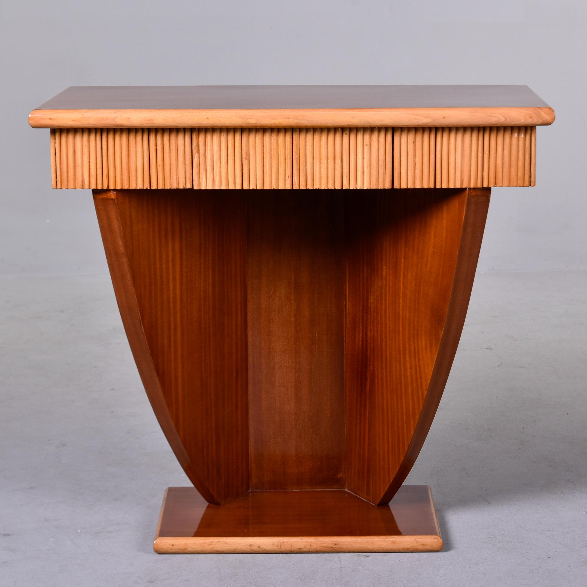 Found in France, this circa 1940 small Art Deco console features a satinwood base with a glossy finish and contrasting blond border and reeded apron with single small center drawer. Unknown maker. 

Very good overall vintage condition.