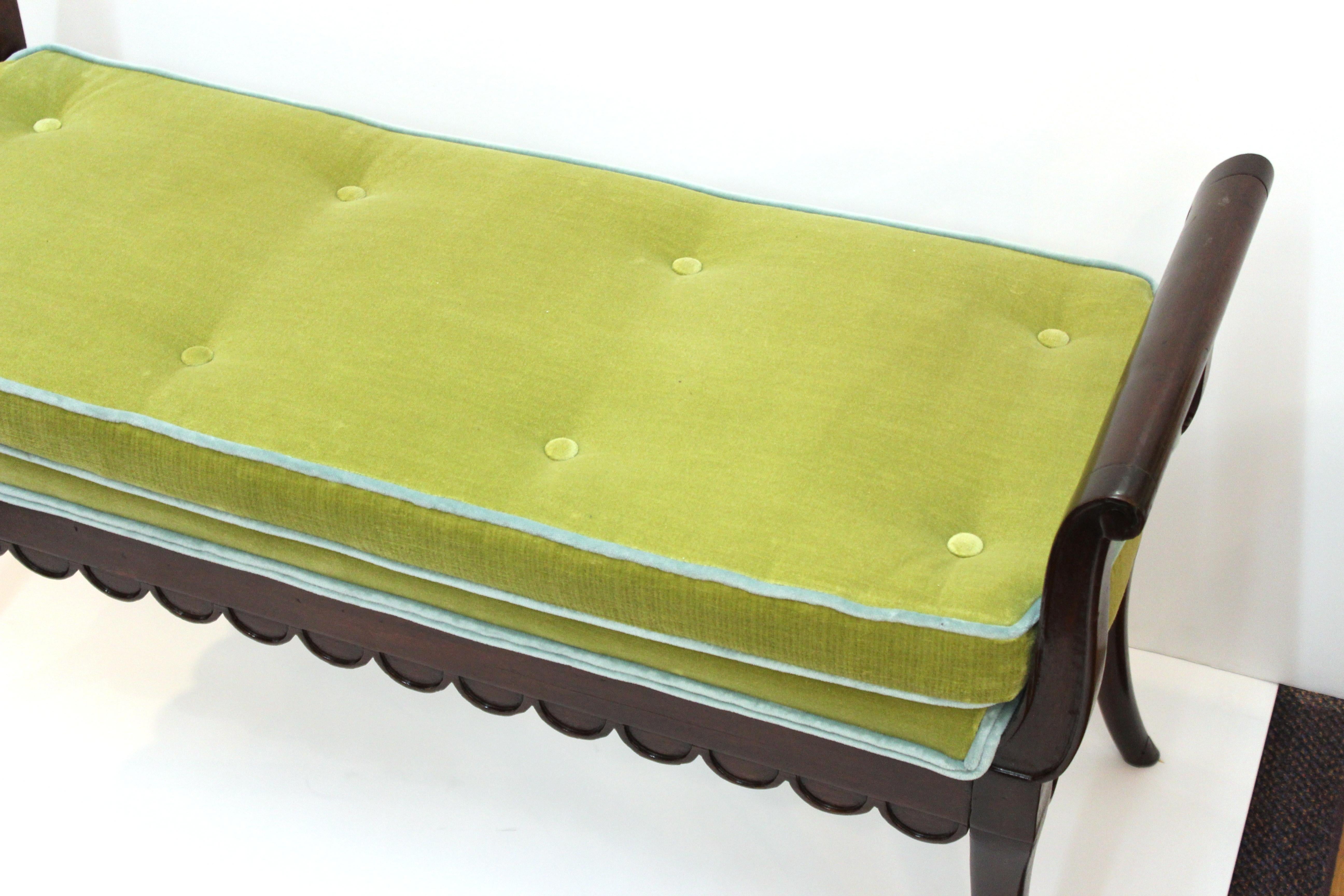 American Art Deco period bench in mahogany, with scalloped lower edges. The piece has handles on the sides and comes with a newly reupholstered cushion in green and blue velvet. Made in the United States during the 1920s, the bench is in great