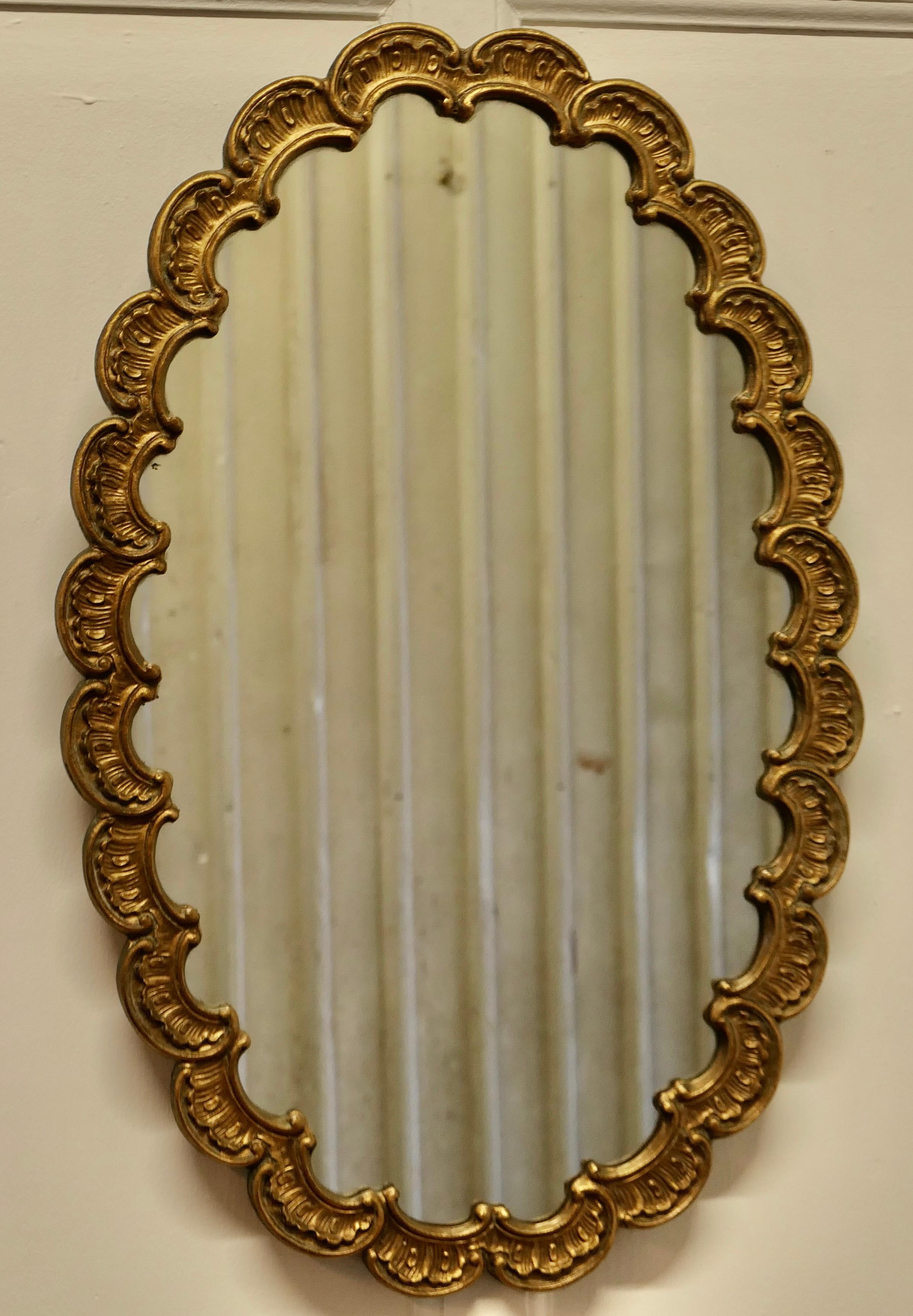 Art Deco Scalloped Oval Mirror 

A lovely piece, the mirror is oval with a deep scalloped edging forming the 2” wide frame
This unusual mirror frame it is gilt over gesso and has a look all of its own 
The Mirror is 29” tall and 20” wide
MS173.