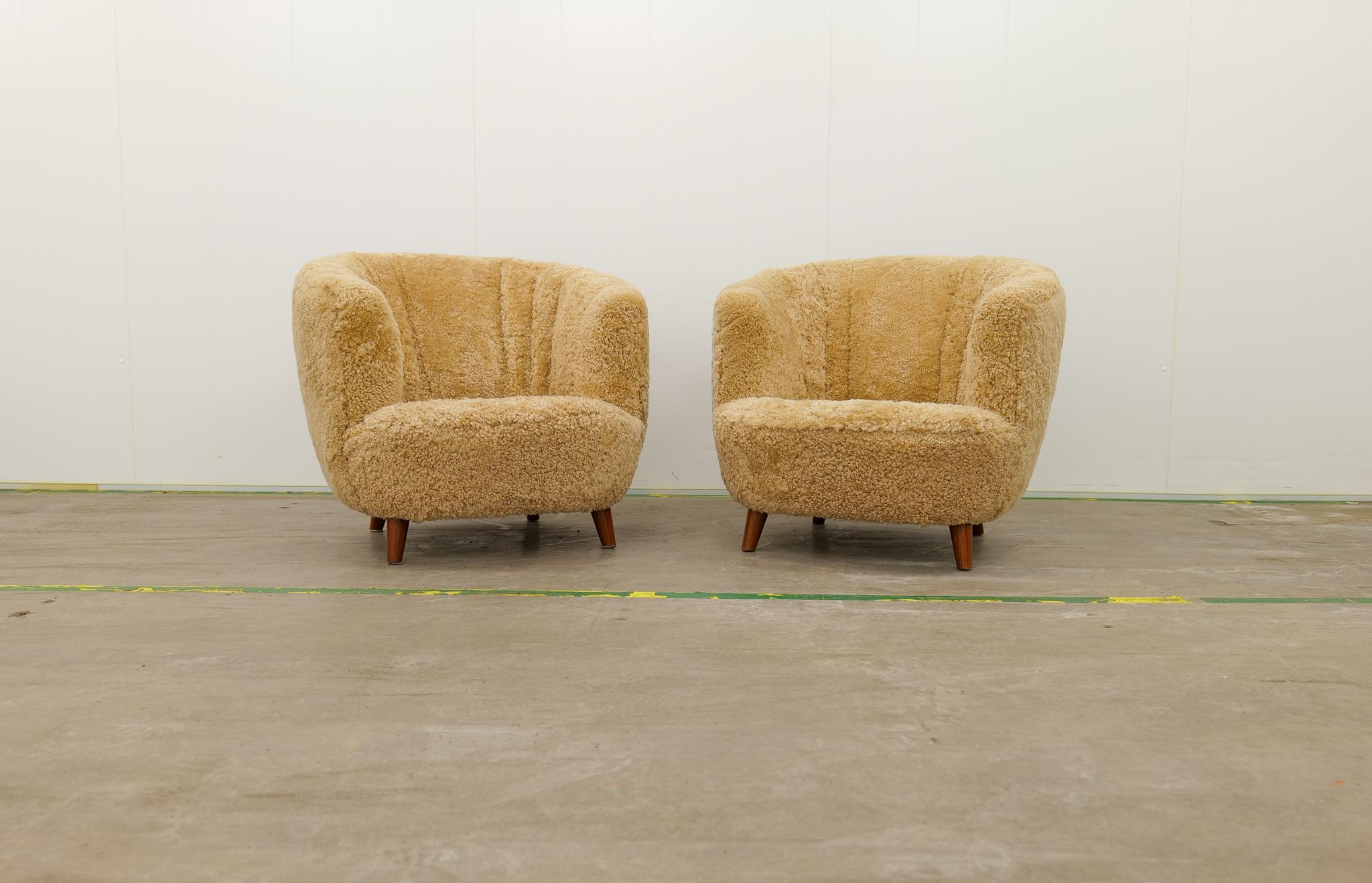 These two wonderfully rounded crafted chairs were made in Norway 1940s and design by Peter Iversen Langlo. The chairs made with stained birch legs and honey colored sheepskin-shearling has been redone with all new upholstery with quality