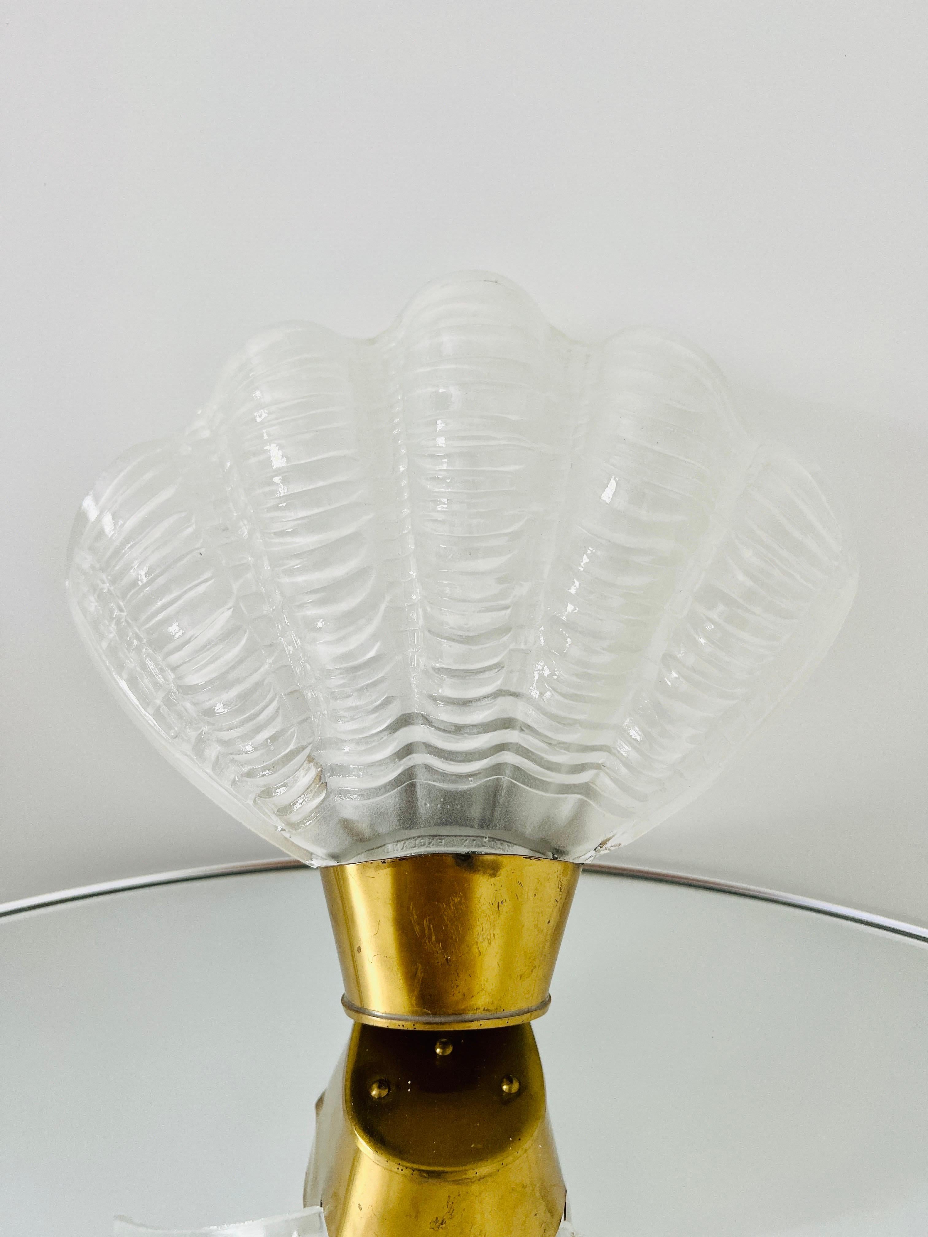 1930's Art Deco sconce with elegant shell design. The sconce is comprised of white hand molded frosted glass with fluted details and stylized ridges in the form of a sea shell.  Features a petite brass metal frame and fitted with one light.

