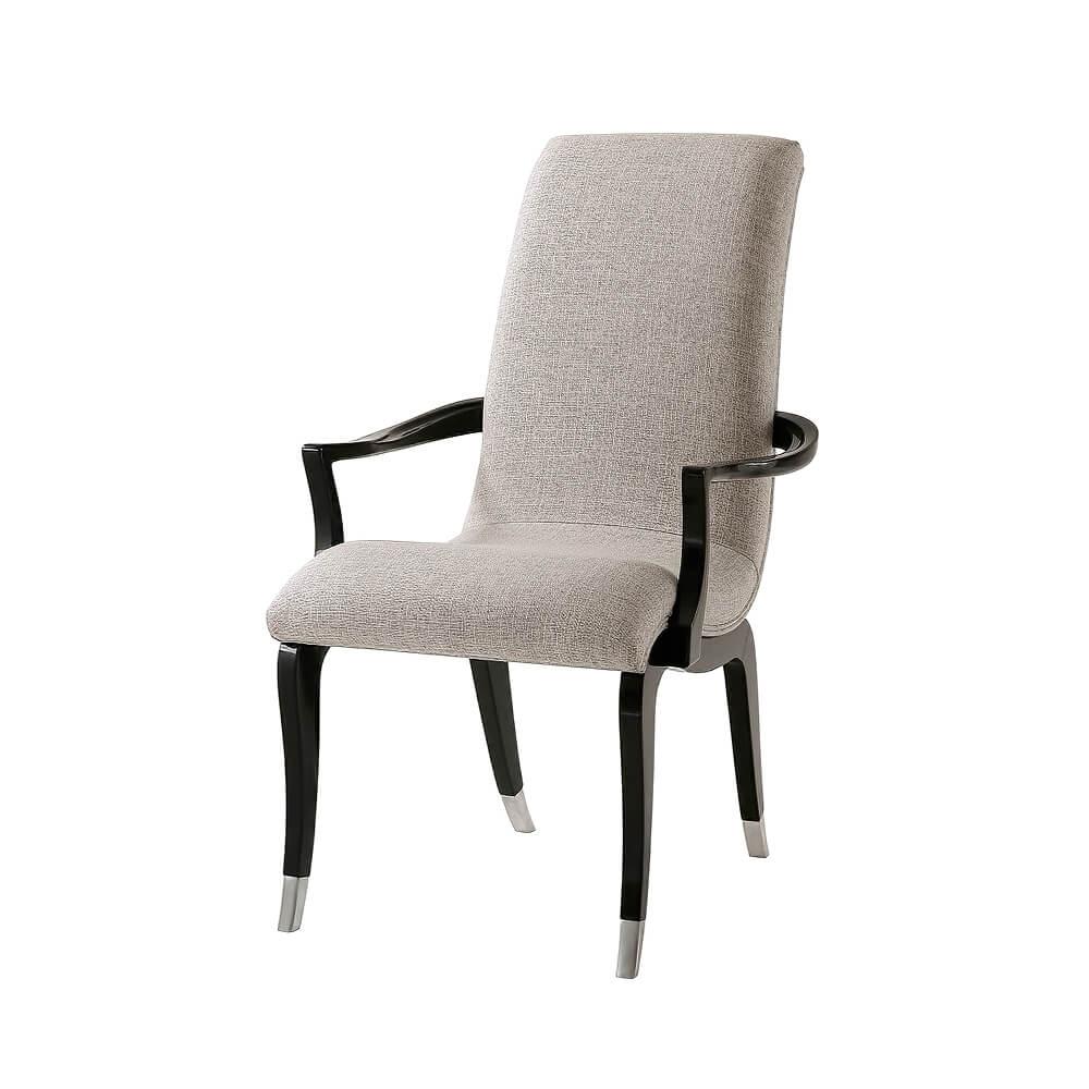 The Art Deco style scrolling armchair with an upholstered seat and back with carved and scrolled arms on serpentine and sabre leg supports in a black lacquered finish with polished nickel caps to the feet. 

Armchair dimensions: 24.25