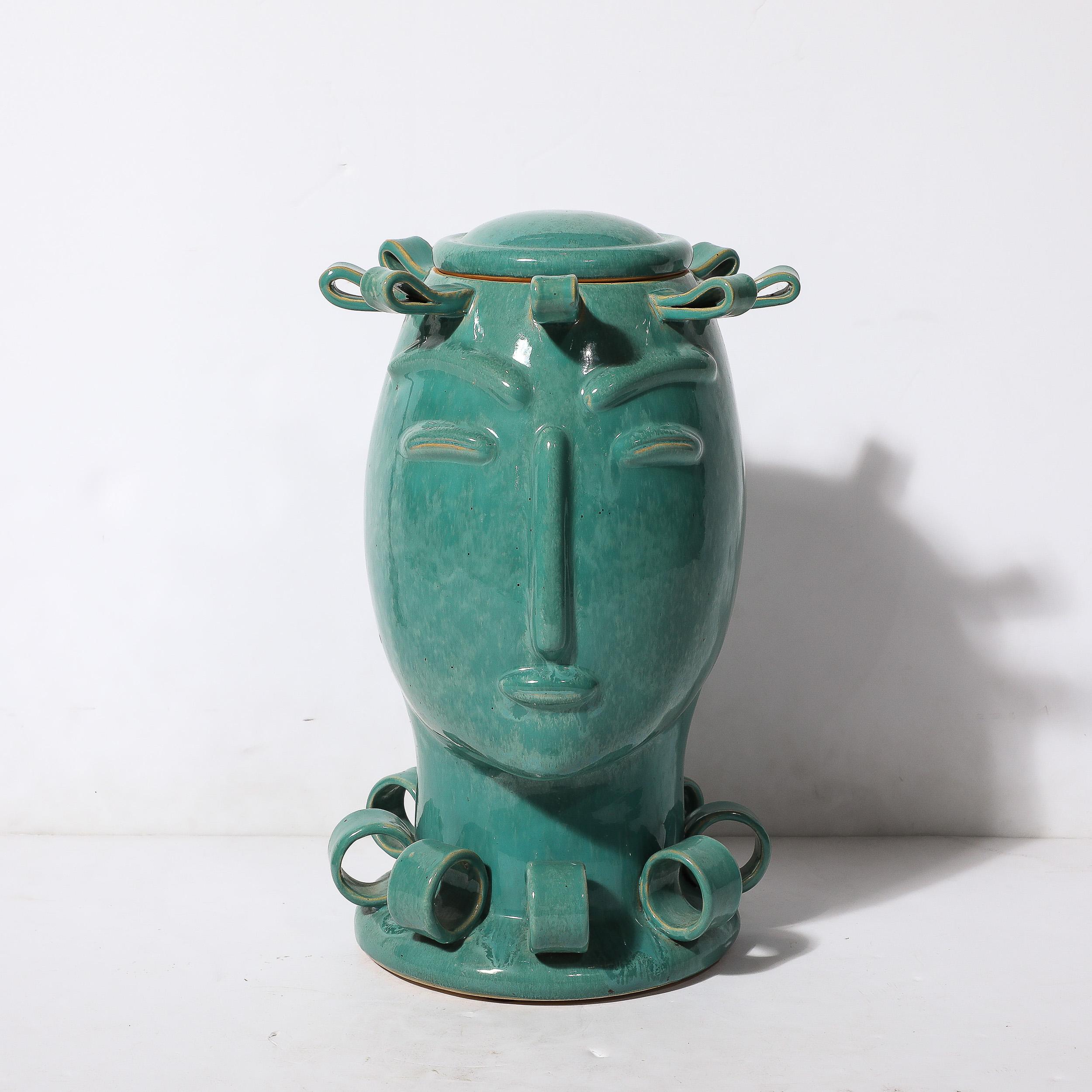 This unique and stunning Art Deco Sculptural Ceramic Vase of Head in Turquoise Jade W/ Ribbon Detailing originates from France, Circa 1930. Formed in beautifully abstracted minimal geometric motifs comprising the facial features and ribbon form