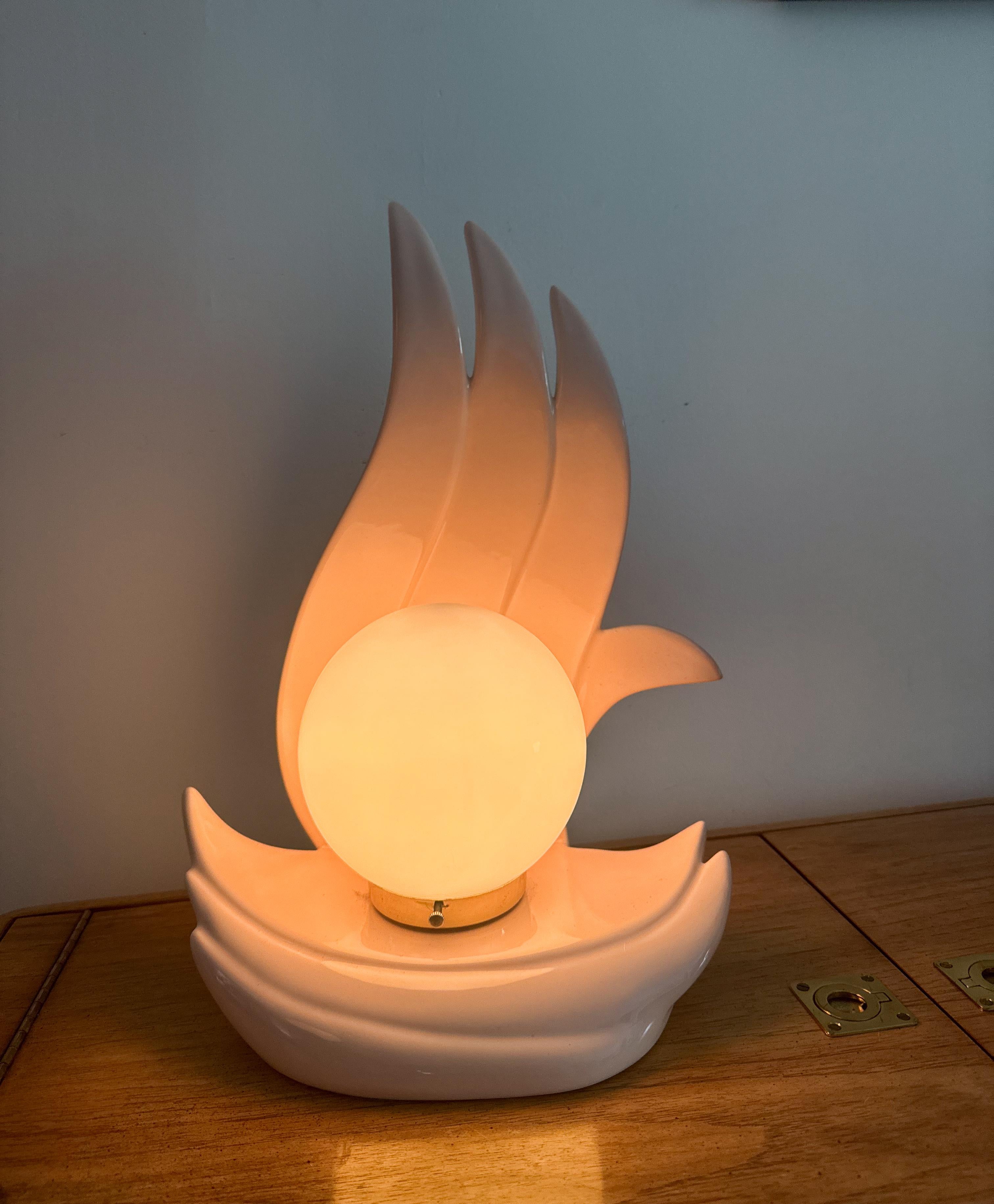 Une étonnante lampe de table à flamme d'inspiration Art déco, fabriquée en céramique rose tendre avec une silhouette sculpturale. Le design présente des formes en forme de flammes qui s'élèvent de façon spectaculaire derrière un globe central en