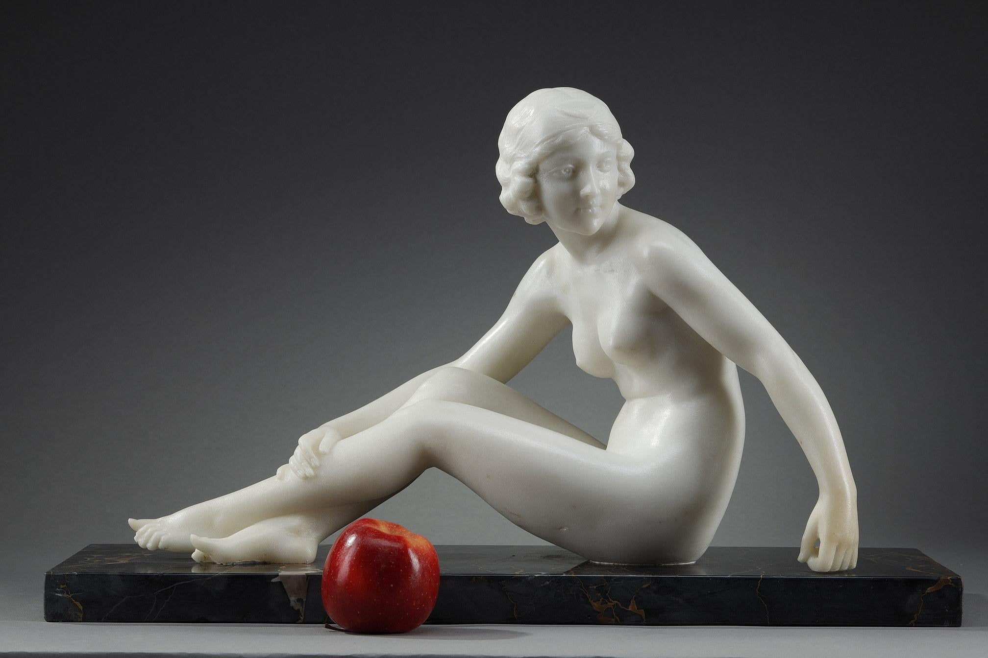 Art Deco Sculpture in white mabre after PUGI. It represents a nude woman sitting in a sensual way. Her short and curly hair, in the fashion of the Roaring Twenties, is topped with a headband showing a crescent moon. This may be a representation of