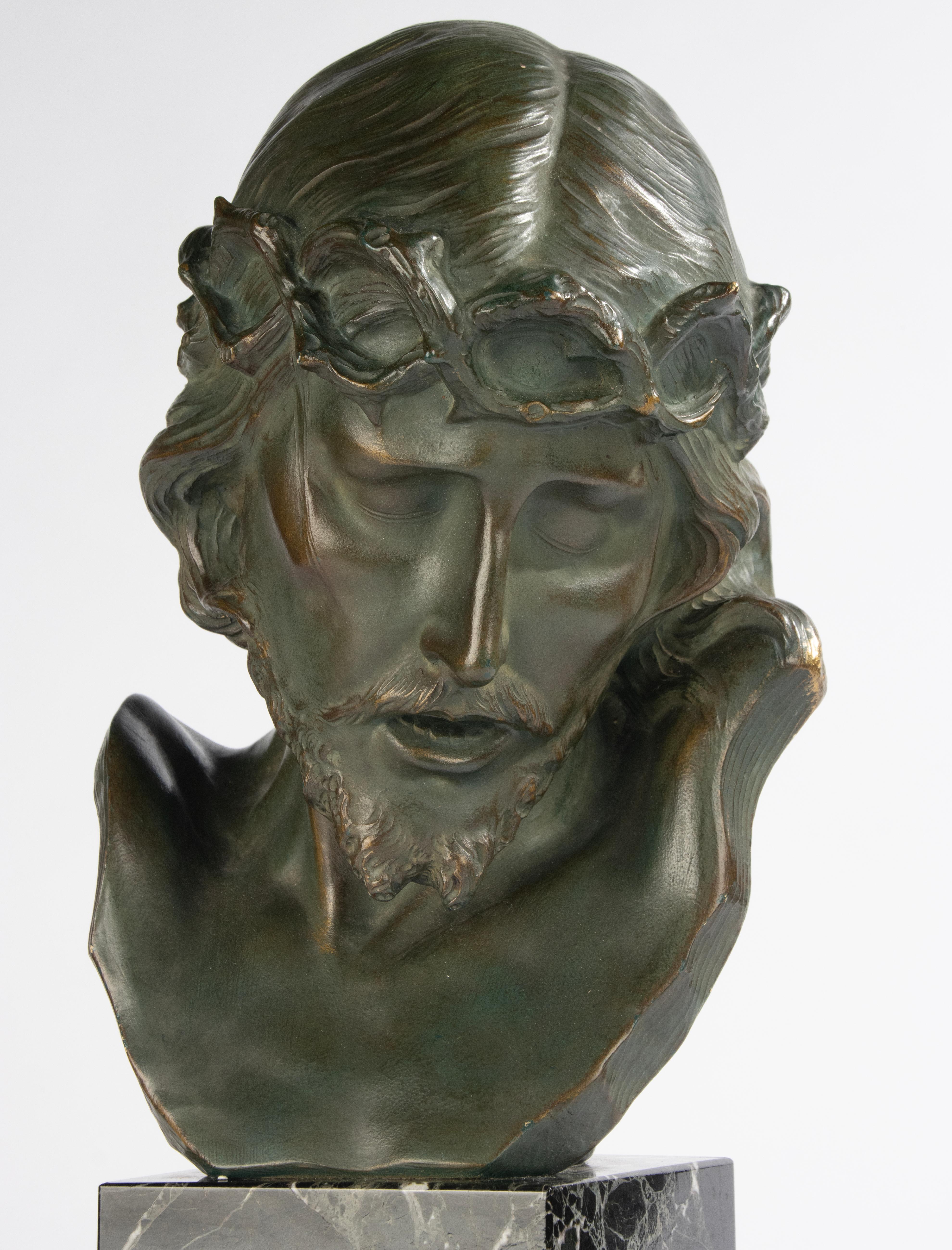 Sculpture très expressive de Jésus-Christ avec une couronne d'épines, datant de la période Art déco. Le buste est en terre cuite avec une patine verte couleur bronze et des accents dorés. Sur un socle en marbre. Signé au dos. Fabriqué en Belgique,