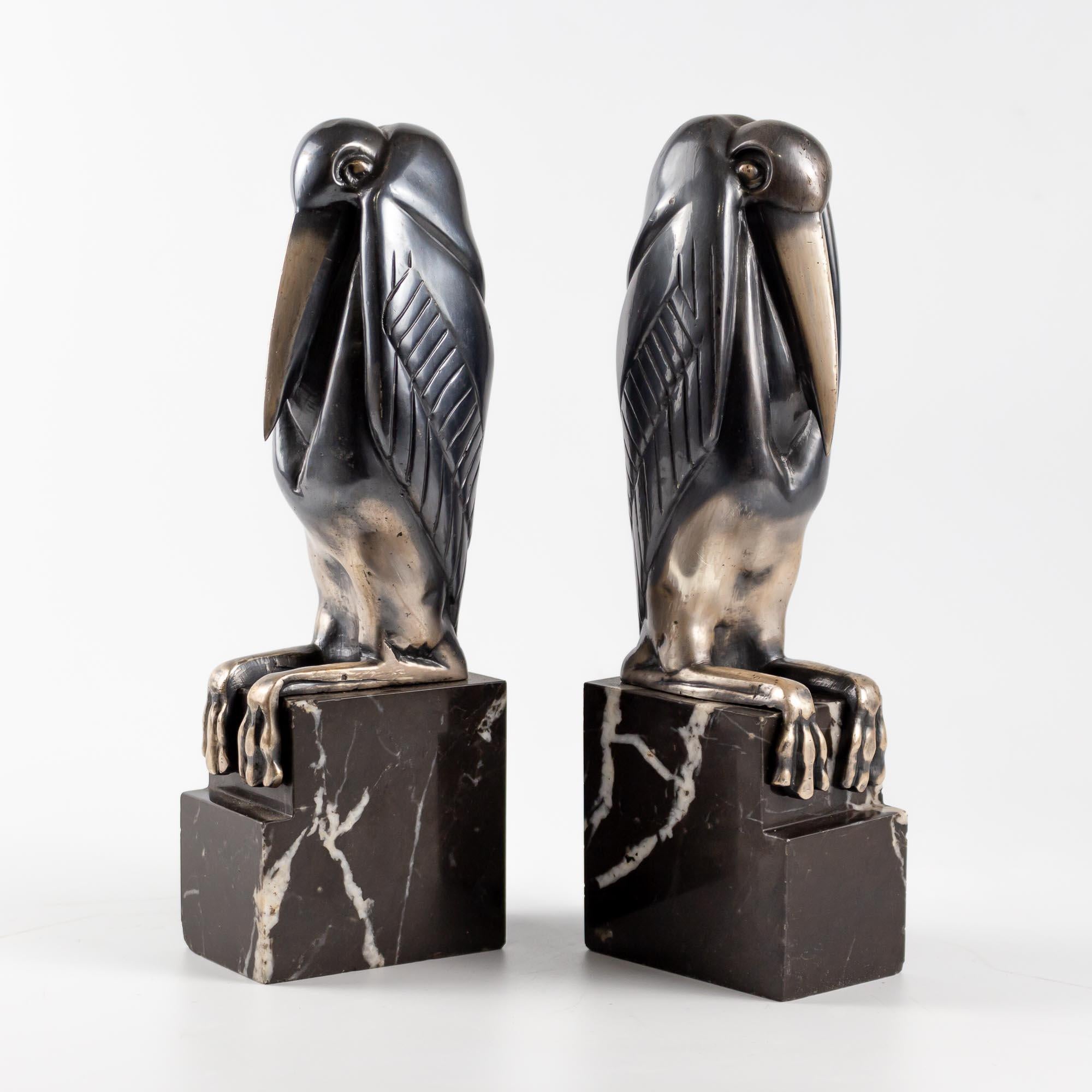 
Ein Paar Art Deco versilberte und patinierte Bronze  Buchstützen von Marcel-Andre Bouraine, um 1930, modelliert als sitzende Marabu-Störche, auf gestuften Marmorsockeln, signiert  A.Bouraine