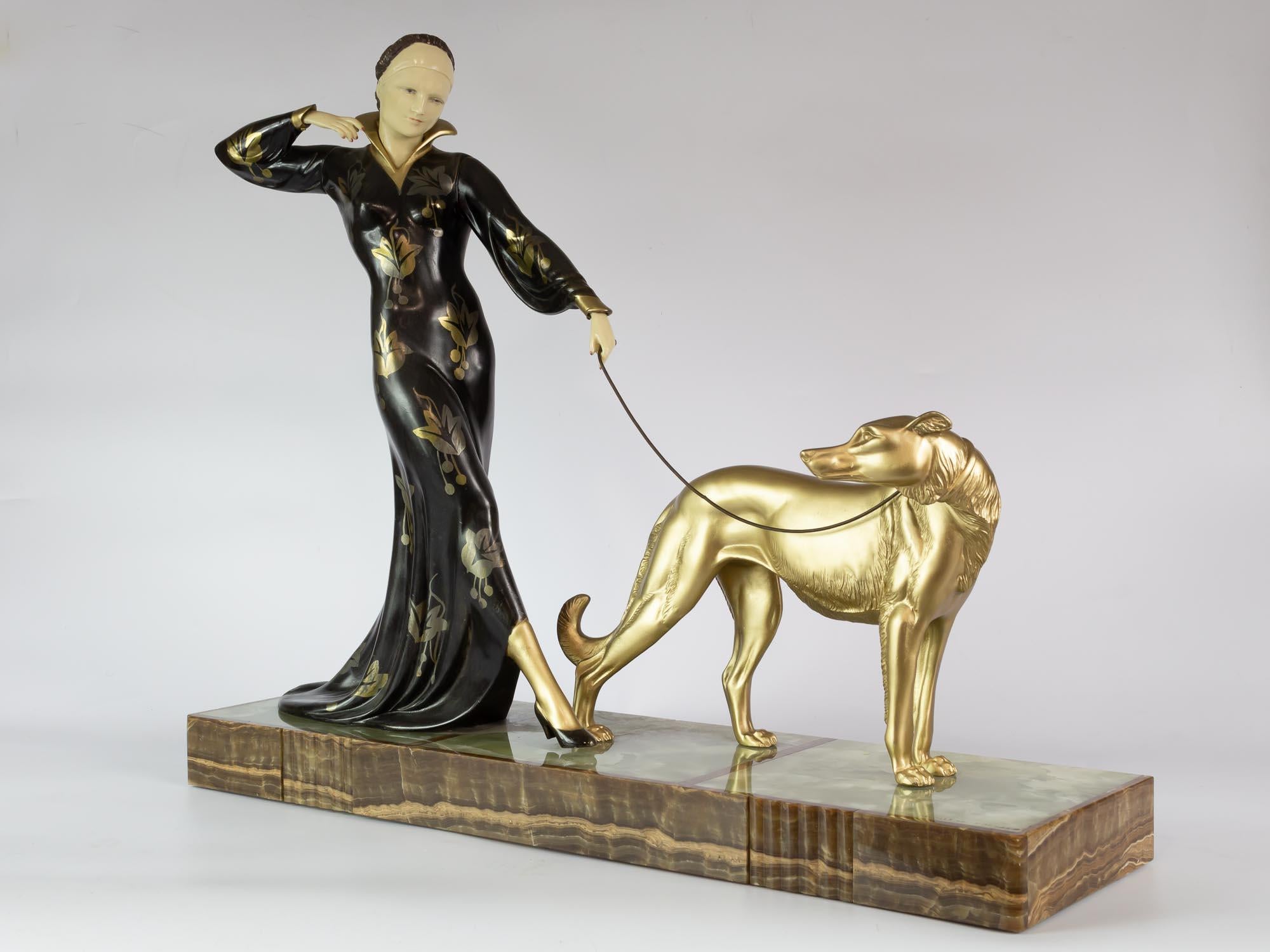 Art deco sculptural group in ivorine and metal patinated metal and gilded  with an onyx plate.
Signed by Menneville et Rochard (Ugo Cipriani and Irenée Rochard). The lady  was modeled by Cipriani and barzoi by Irénée Rochard.
Made in France Ca,