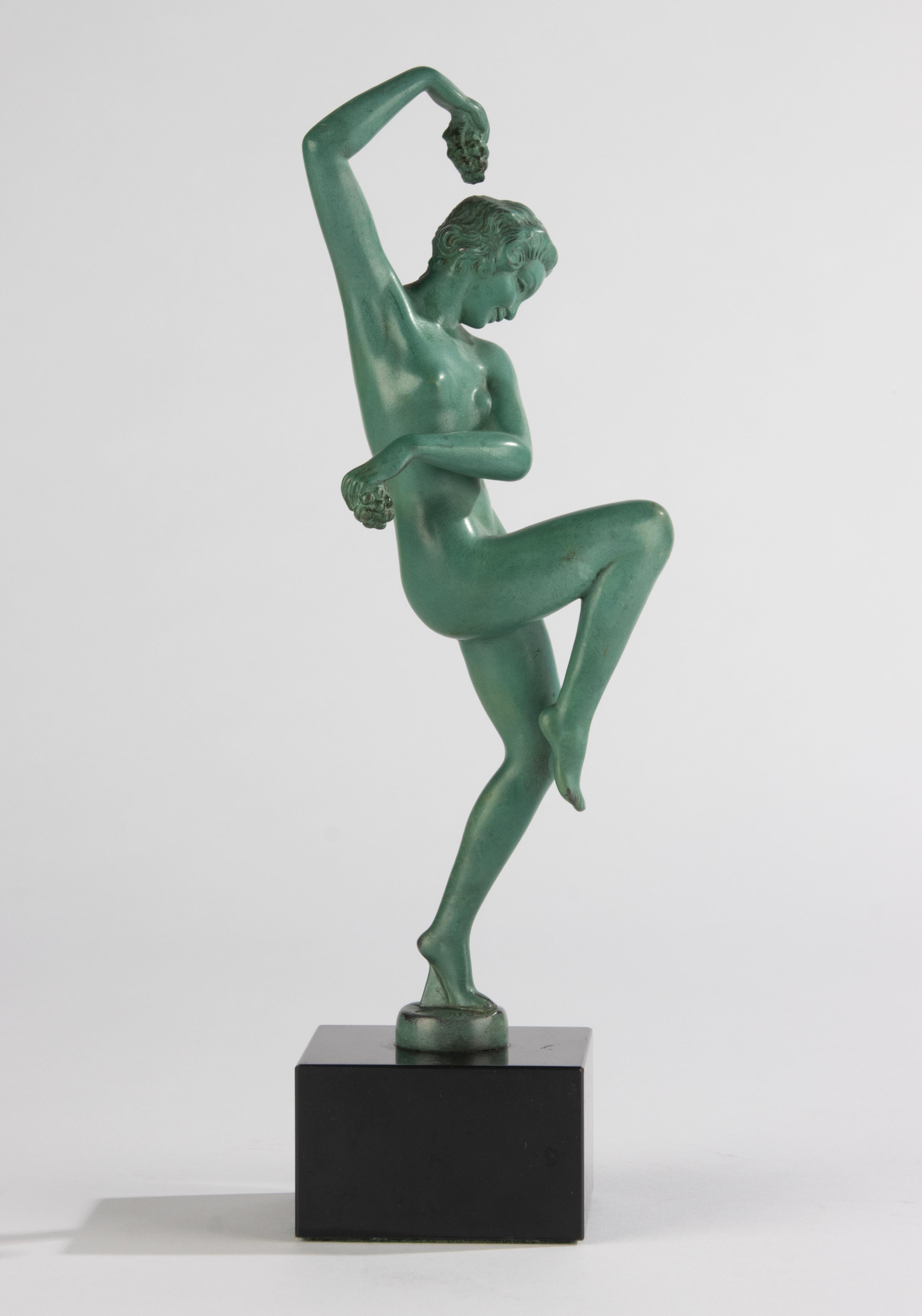 Un'elegante scultura Art Déco di una donna danzante con dell'uva in mano. Raffigura Menade, la seguace di Dioniso. Firmato Denis, fuso presso la fonderia Max Le Verrier in Francia. Realizzato in spelta patinata verde, su un basamento in marmo belga