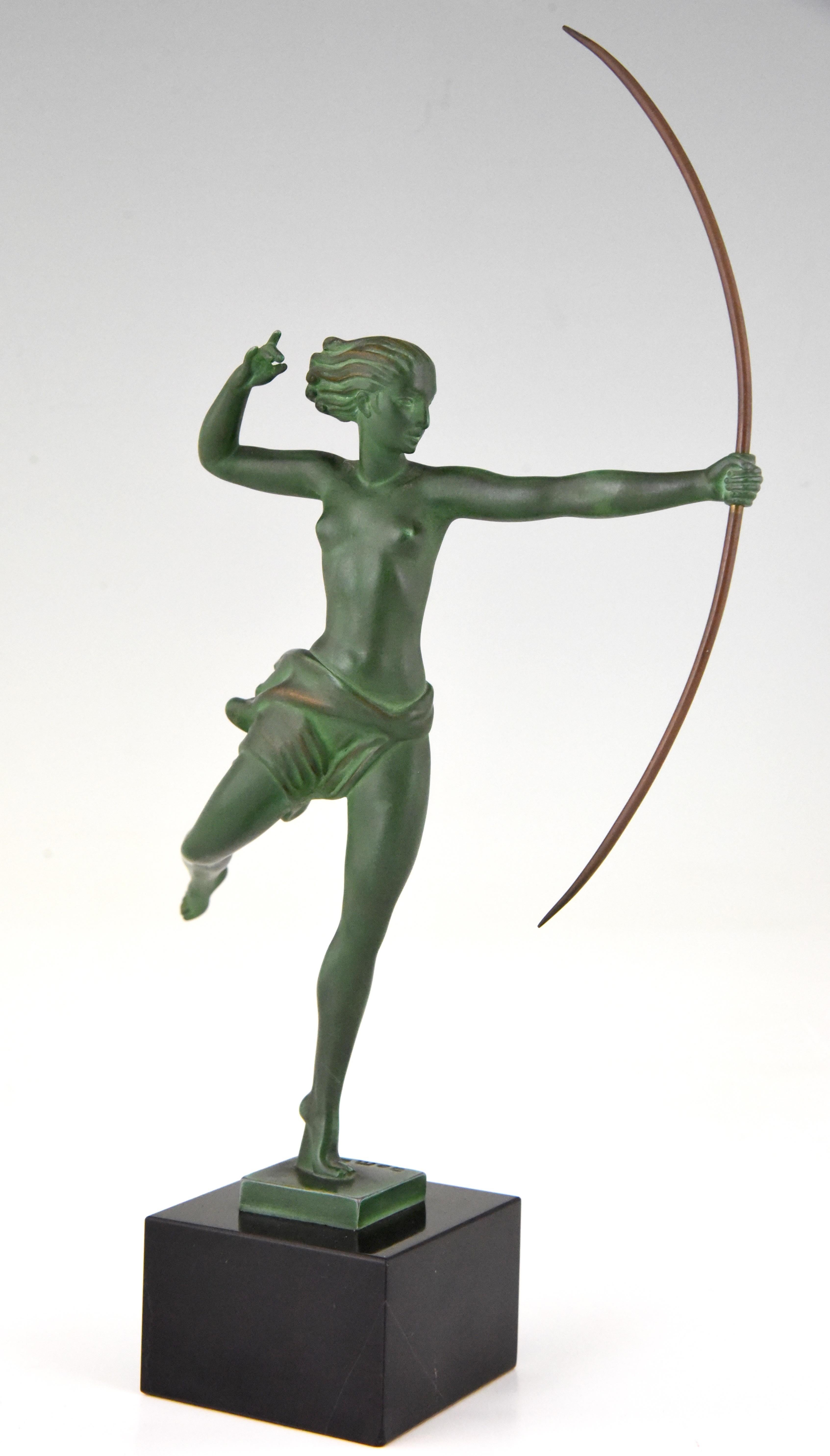 Elegant Art Deco sculpture of a standing female nude with bow, Atalante. By the French artist Jean de Marco, cast by Max Le Verrier.
The figure has a green patina and stands on a fine Belgian black marble base. 

“The dictionary of sculptors in