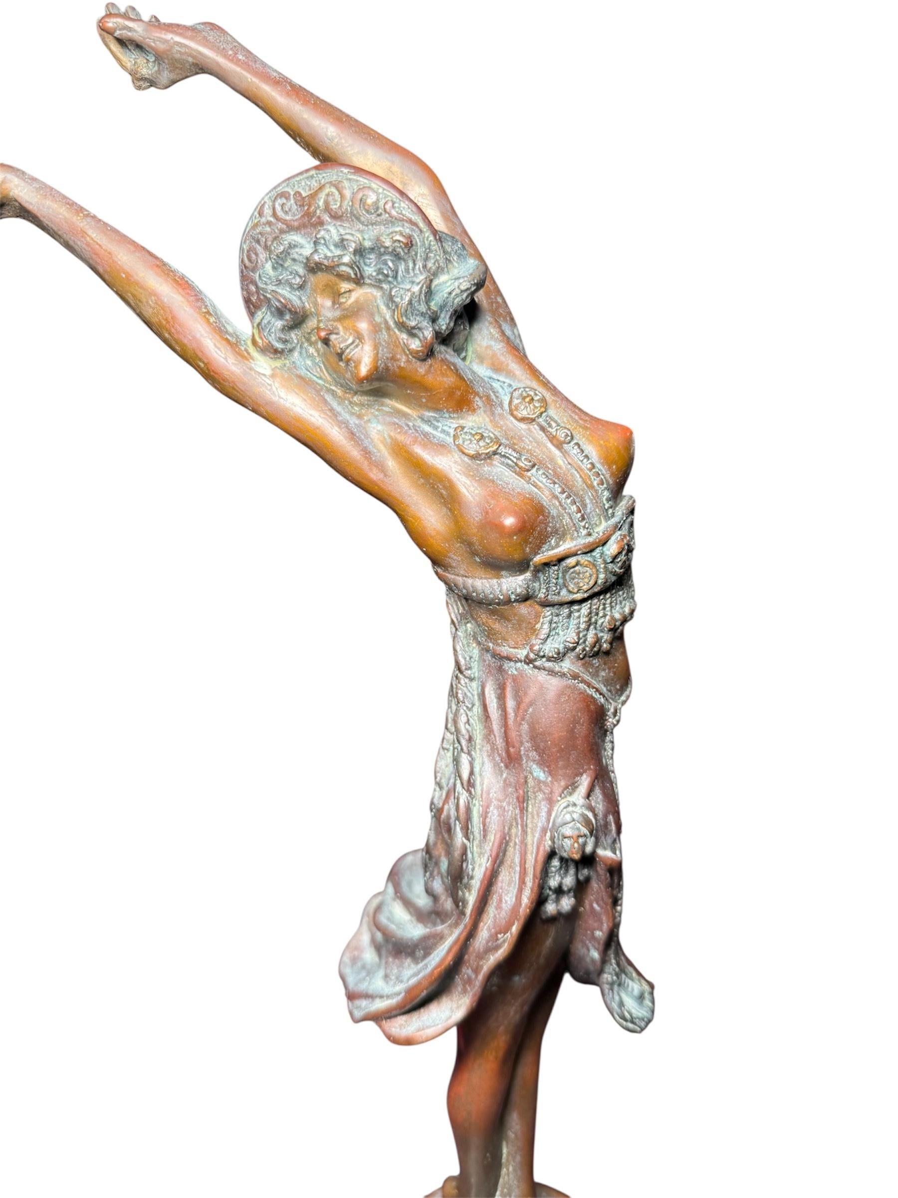 Il s'agit d'une sculpture en bronze d'une danseuse en équilibre d'après Claire Collinet. Elle représente une jeune fille aux cheveux noirs ondulés, vêtue d'une robe courte exotique, dansant sur une plate-forme ronde en bronze décorée d'une guirlande