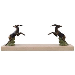 Escultura Art Decó de gamos saltando en metal patinado sobre base de mármol, años 30