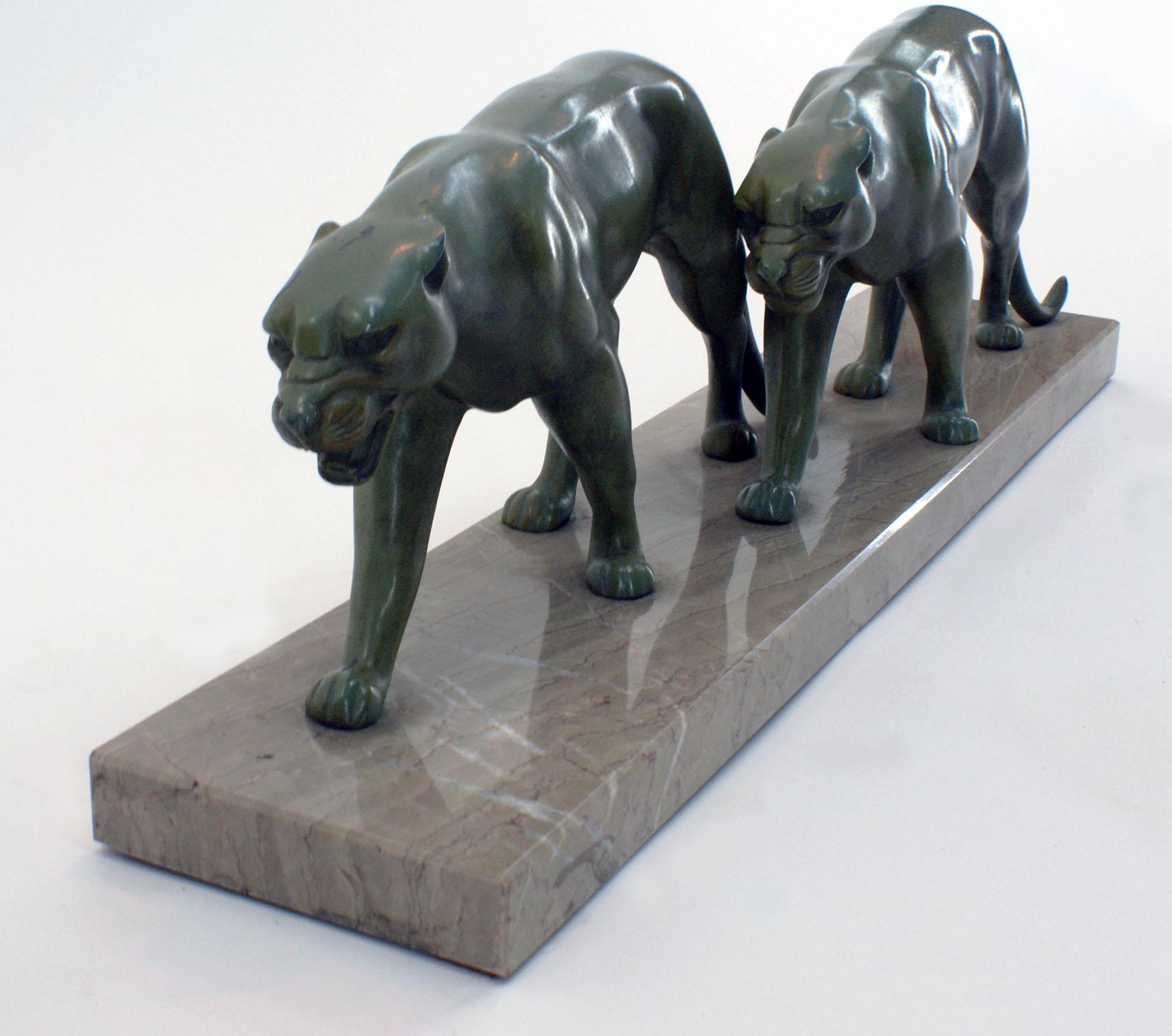 French Art Deco bronze spelter sculpture of two walking panthers attributed to the French artist Alexandre Ouline in art metal green color with lovely patina on a beige color Italian marble terrace.