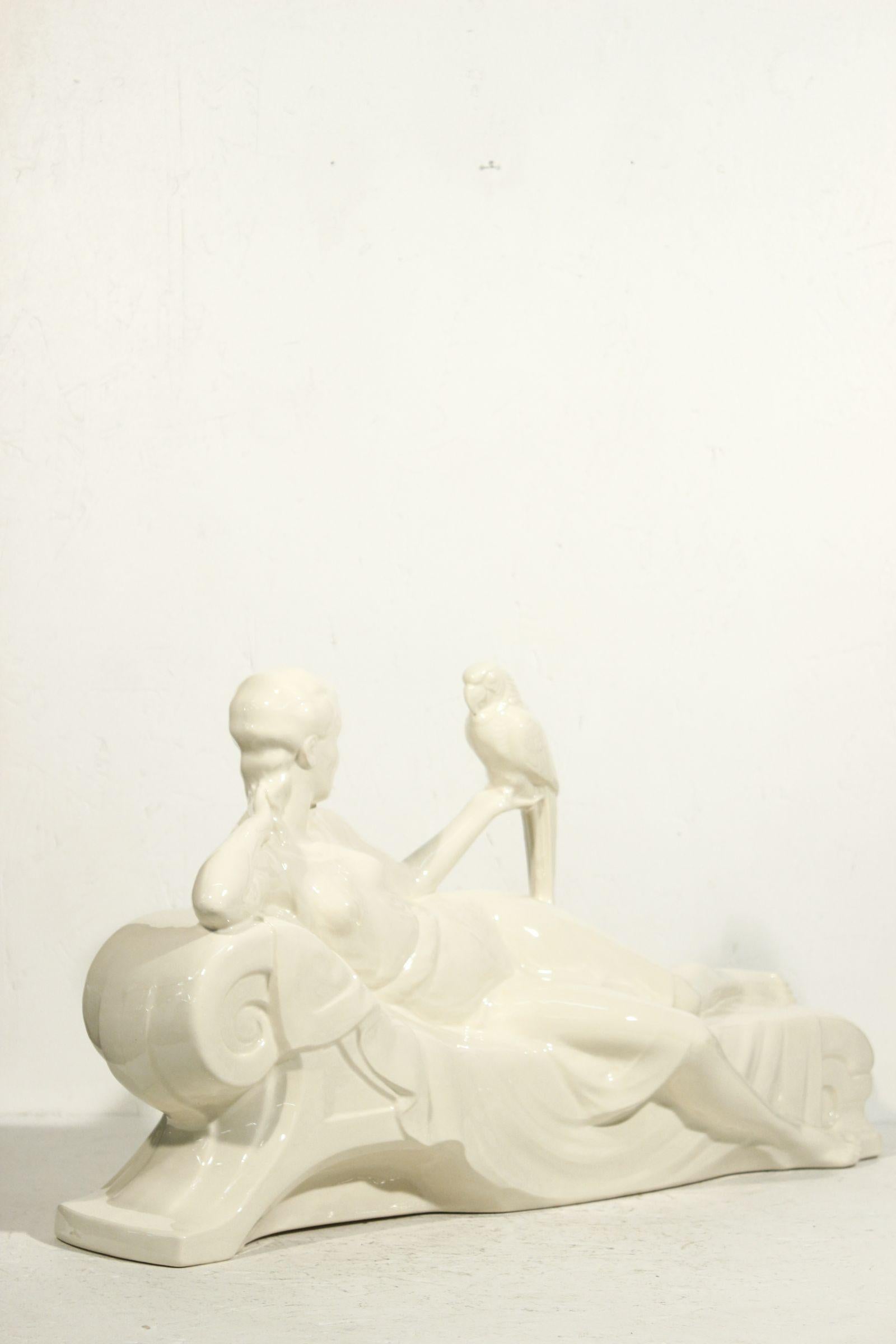 Grande et élégante sculpture d'une femme partiellement drapée, allongée et tenant un perroquet. Rare production de Sarreguemines France vers 1930, issue d'une collection éphémère qui célébrait les années folles des années 1920. 

Très belle pièce de
