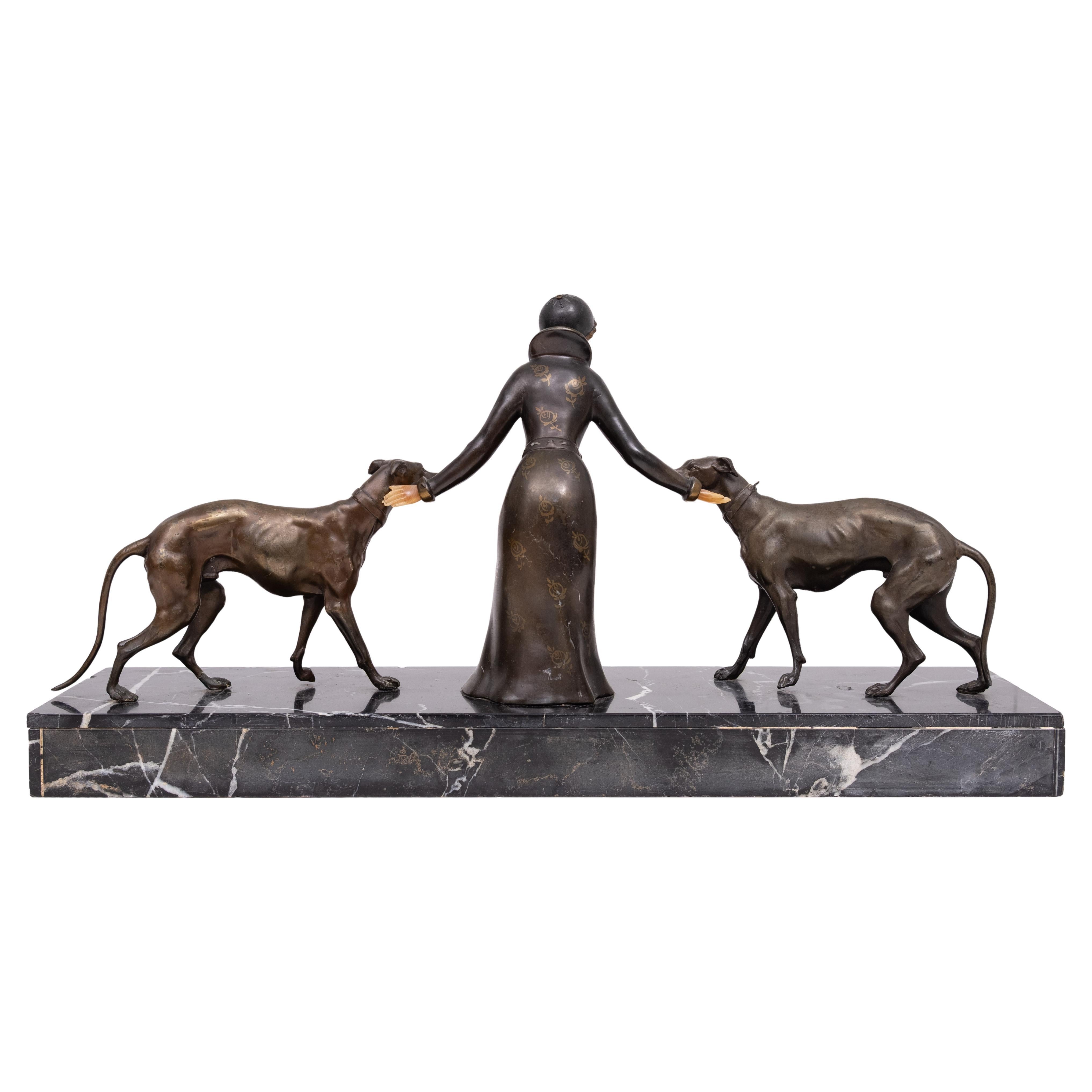 Diese auffällige Original-Skulptur im Art-déco-Stil zeigt eine anmutige Frau, die mit zwei schlanken Barsois spazieren geht, ein Motiv, das für die Eleganz und den Glamour der 1920er und 1930er Jahre steht. Die Figur ist in ein fließendes,