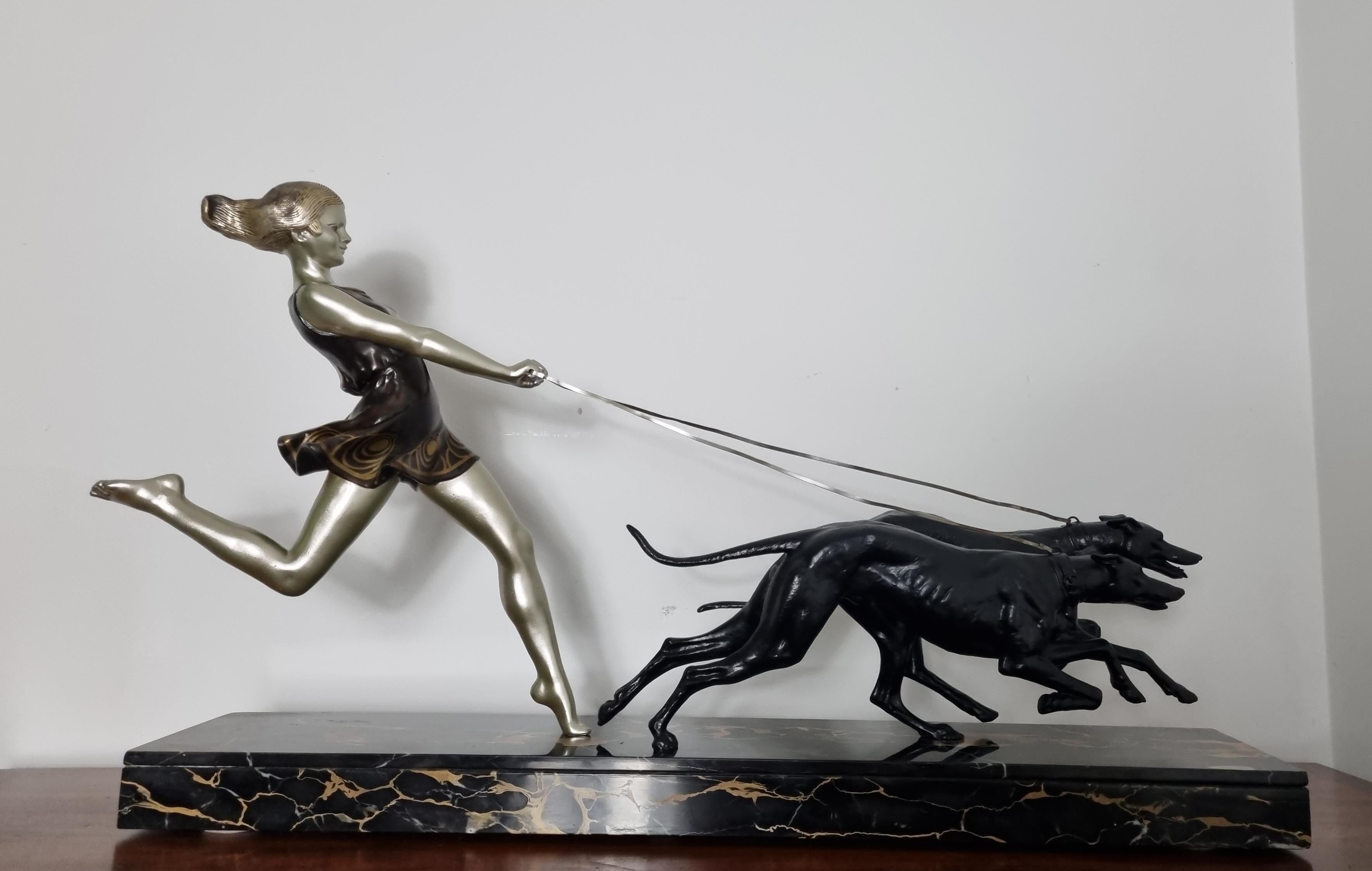 Una scultura originale in stile Art Deco / Ragazza con abito e capelli fluenti che corre con due levrieri affusolati su una base di marmo portoro. Firmato alla base dal noto artista francese Artistics Geo Maxim. Il pezzo che rappresenta la libertà