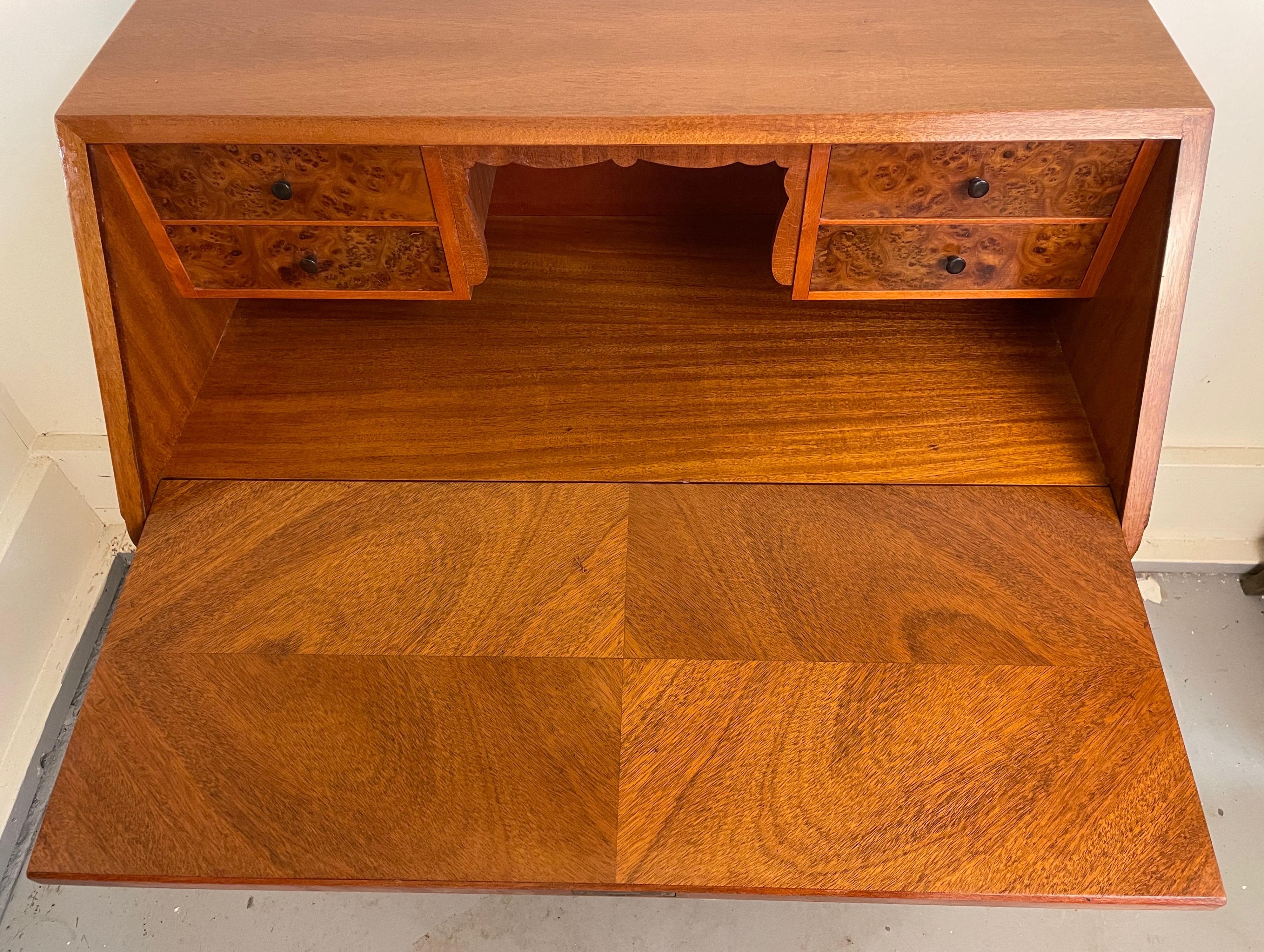 Ein praktischer Schreibtisch, der keine ästhetischen Kompromisse eingeht. Das schöne Mahagoni-Furnier in Buchform ziert sowohl die Innen- als auch die Außenseite des Gehäuses. Die Schubladen im Inneren sind mit genopptem Mahagonifurnier und